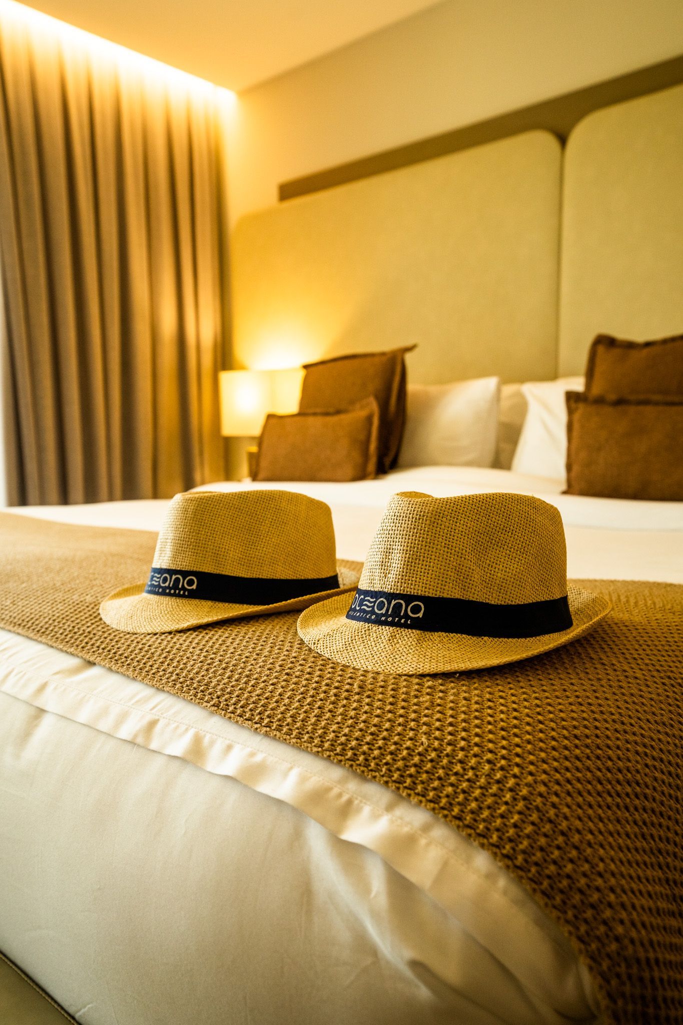 Dois chapéus de palha estão sobre uma cama em um quarto de hotel.