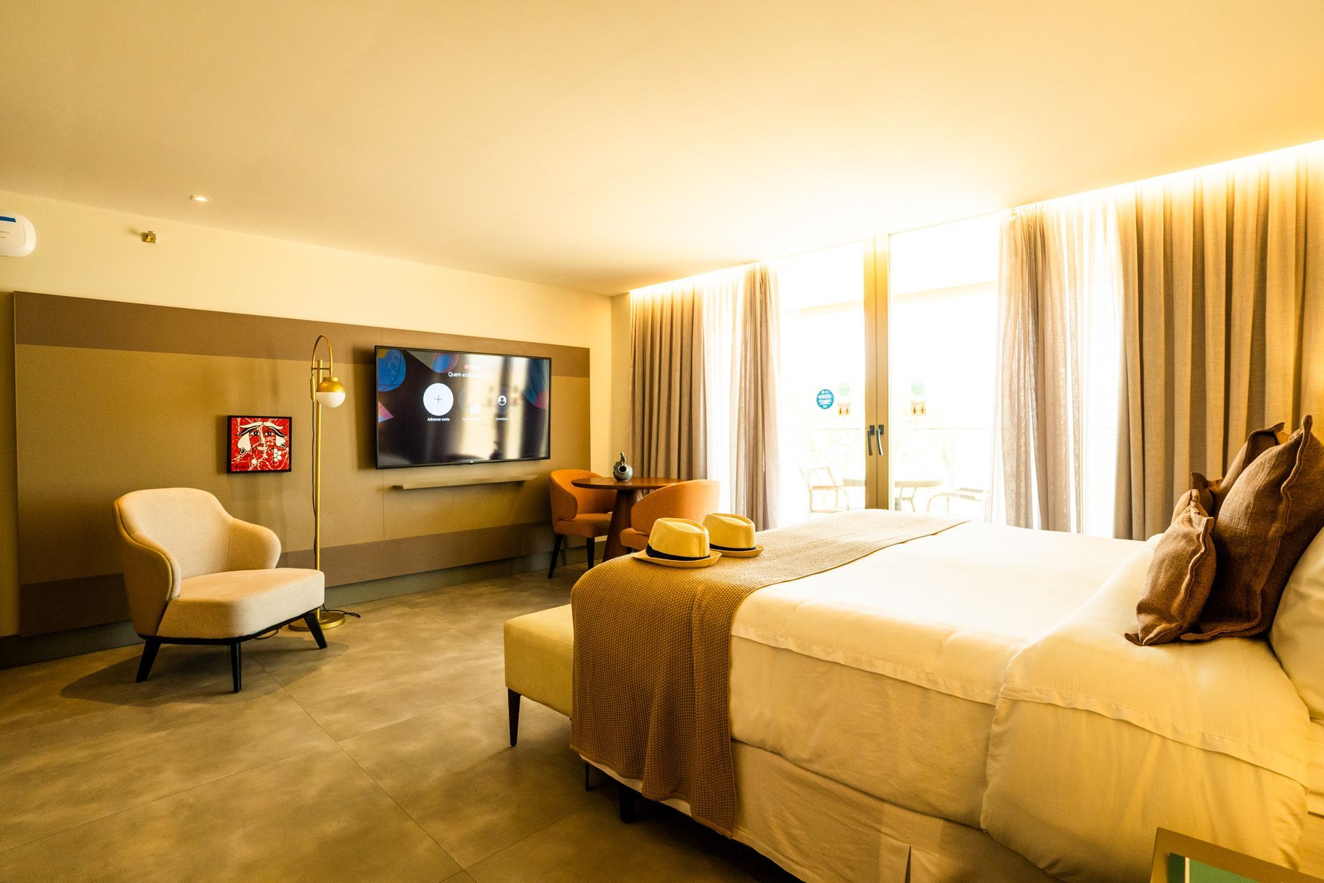 Um quarto de hotel com uma cama king size, cadeiras e uma TV de tela plana.