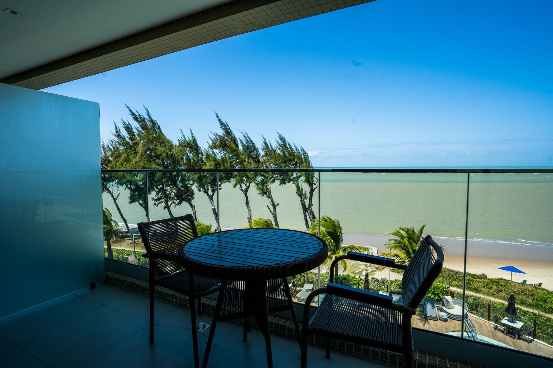 Uma varanda com mesa e cadeiras com vista para o oceano.