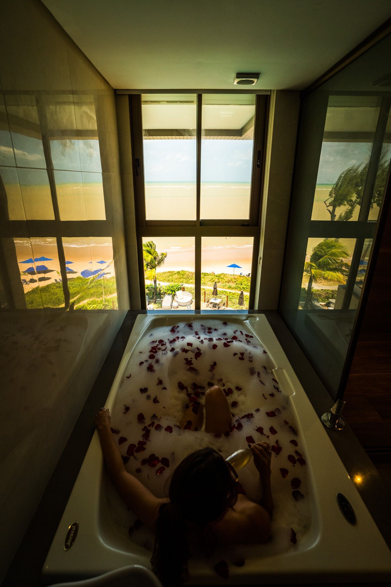 Uma mulher está deitada em uma banheira cheia de espuma e pétalas de rosa.