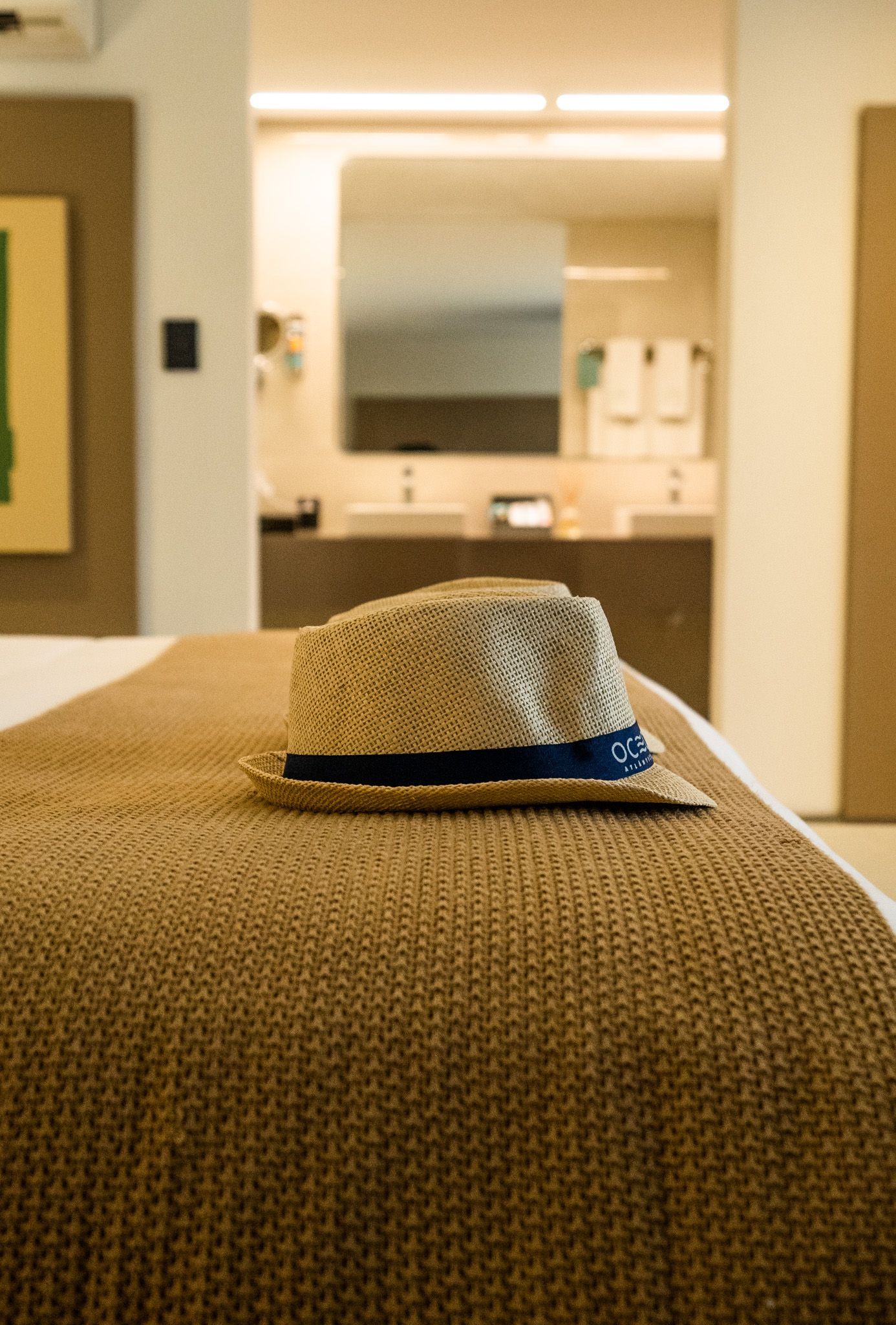 Um chapéu está em cima de uma cama em um quarto de hotel.