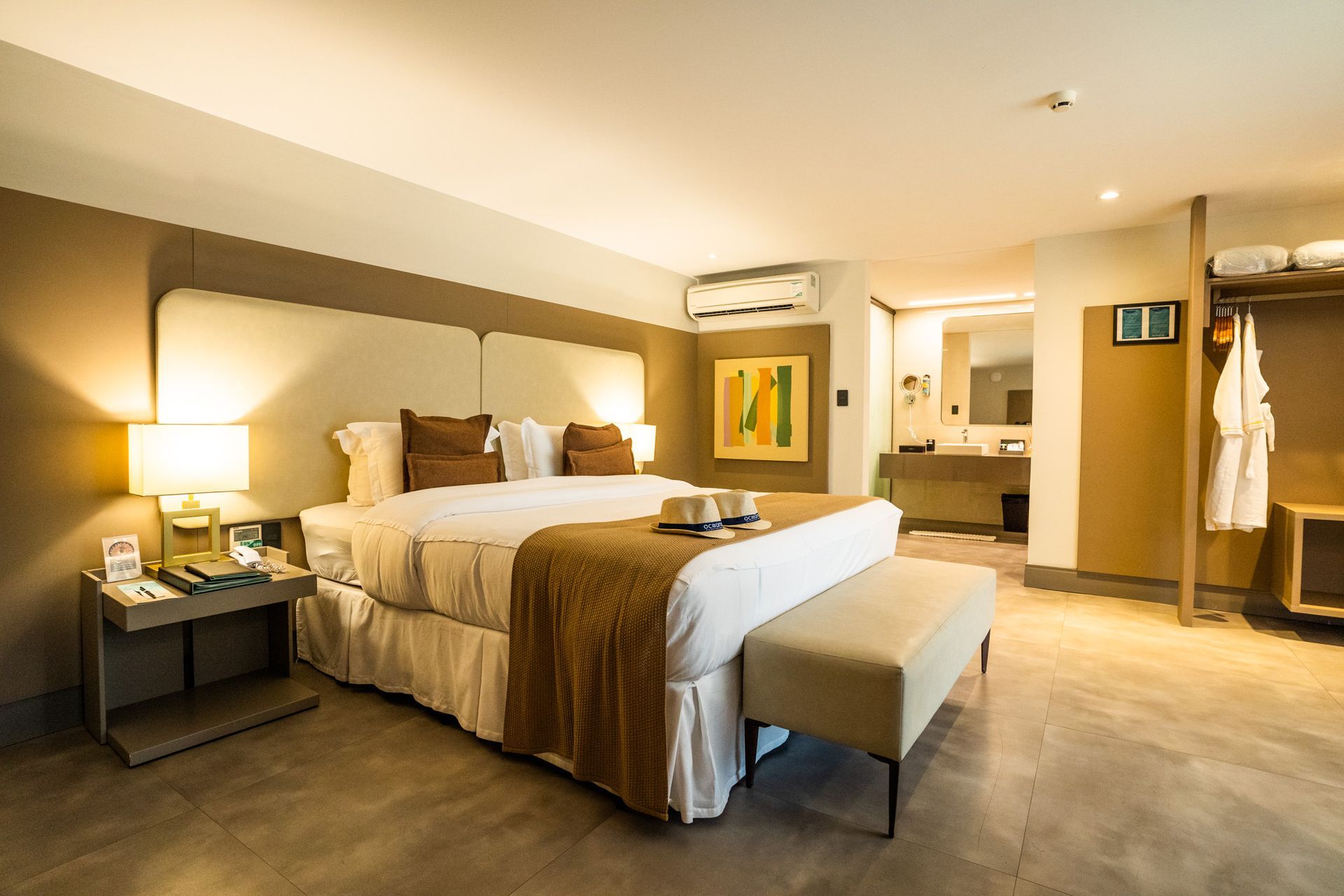 Um quarto de hotel com uma cama king size e um banco.