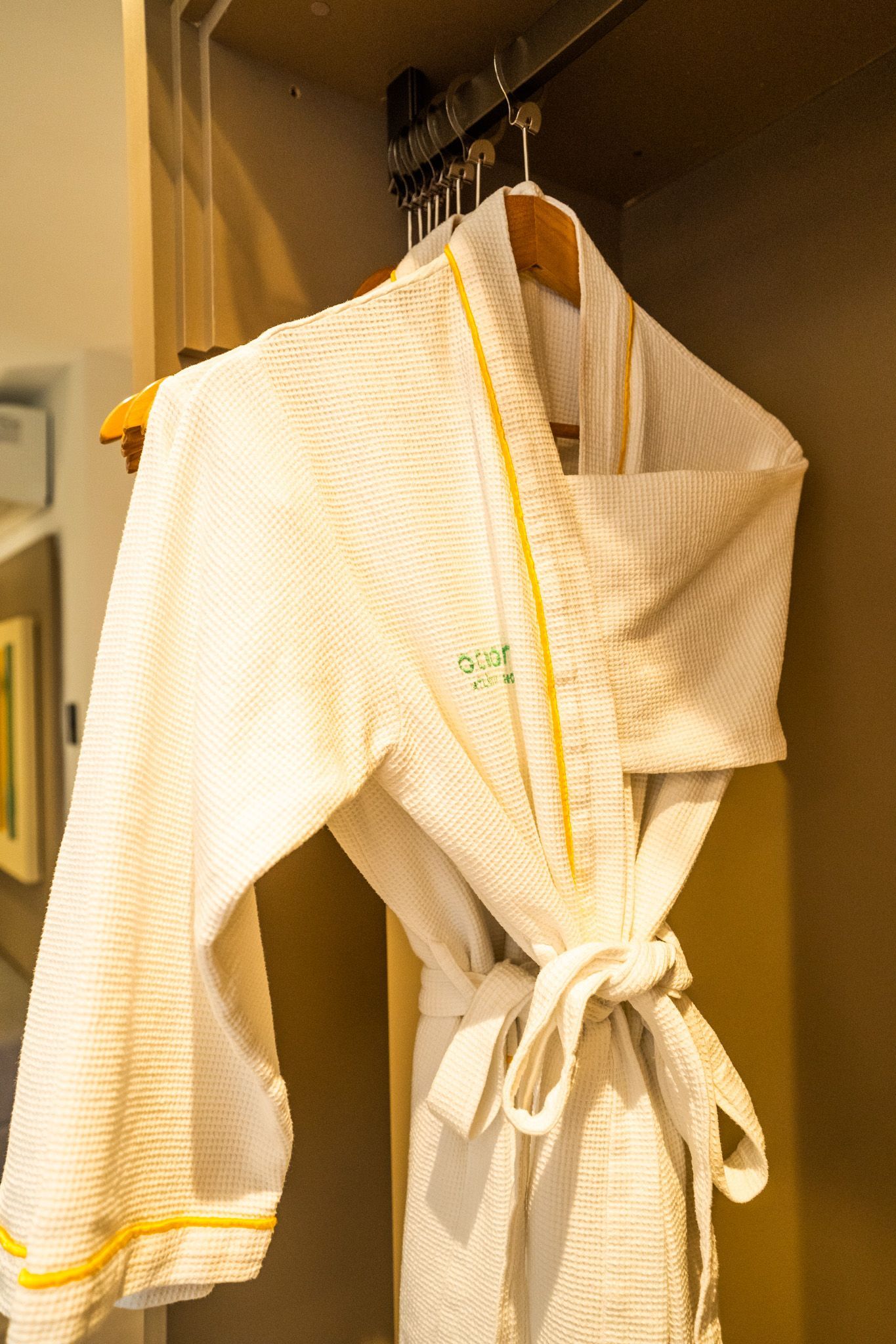 Um manto branco com detalhes amarelos está pendurado em um armário.