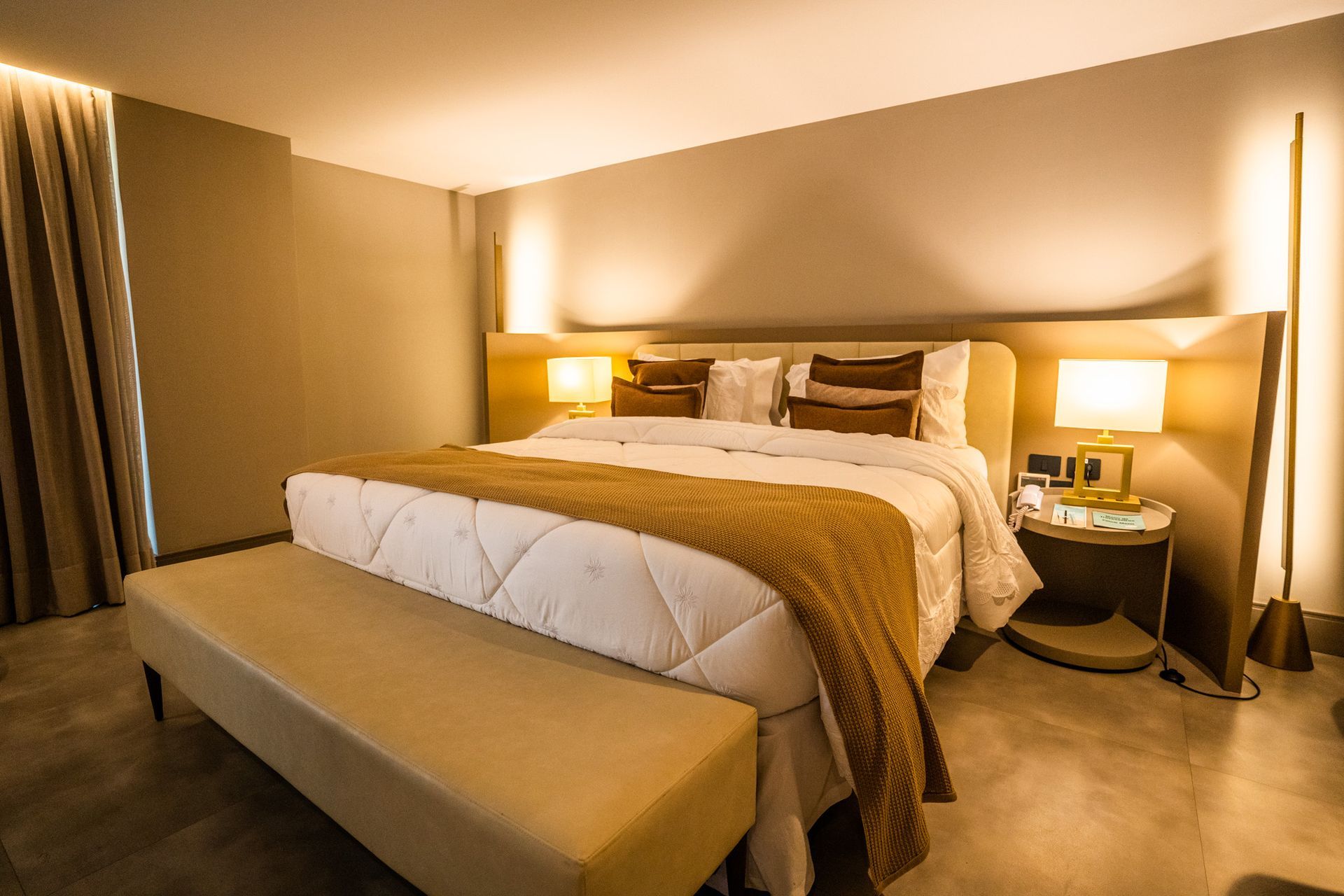 Um quarto de hotel com uma cama king size e um banco.