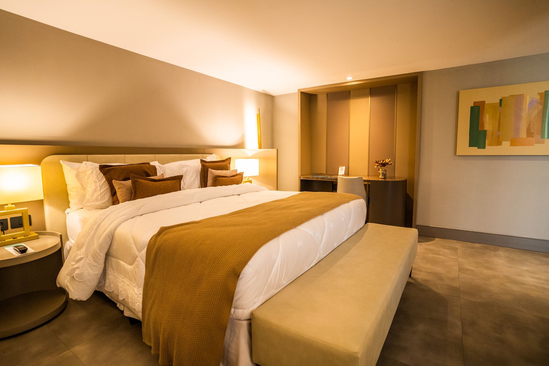 Um quarto de hotel com uma cama king size e um banco.