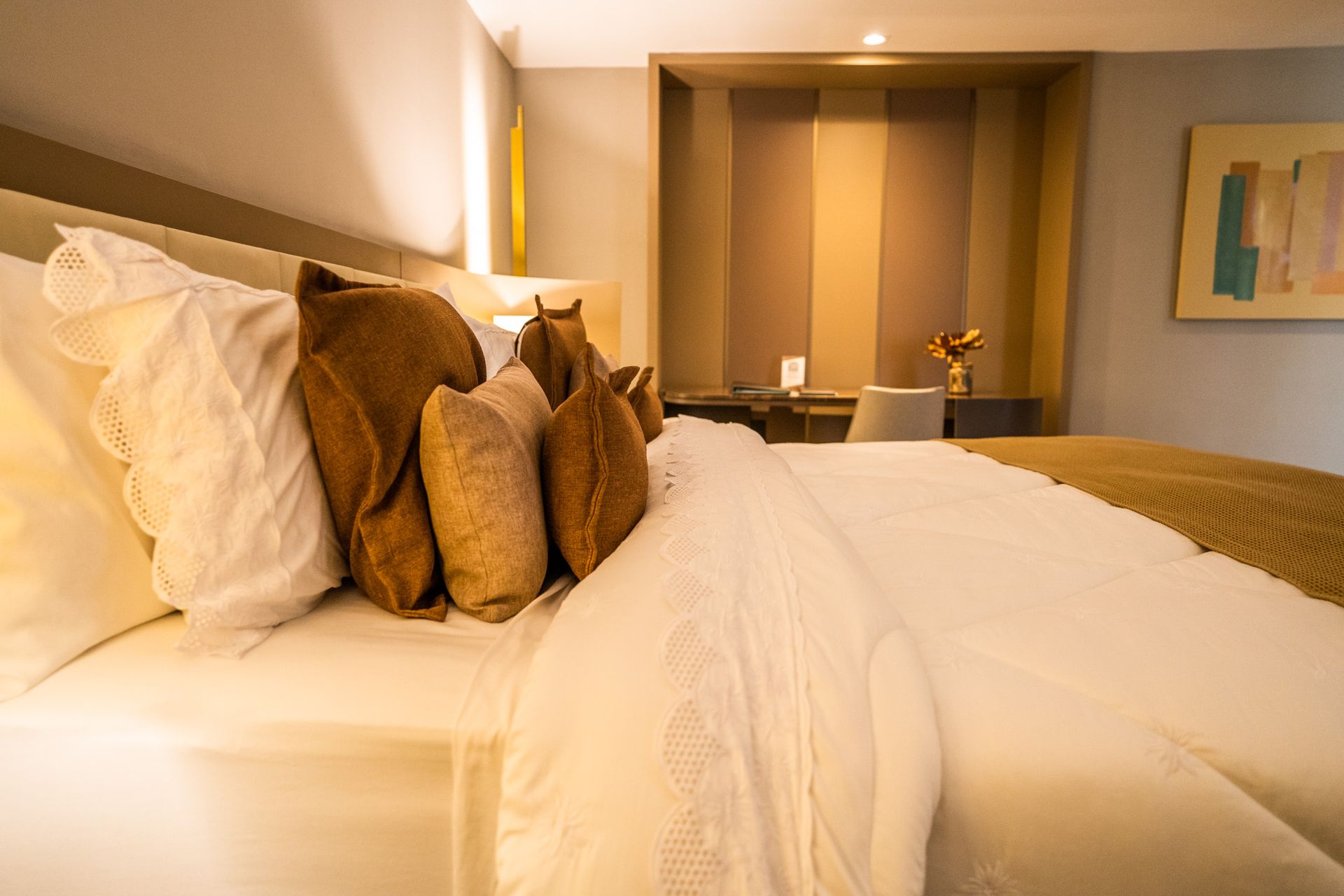 Uma cama com lençóis brancos e travesseiros marrons em um quarto de hotel.