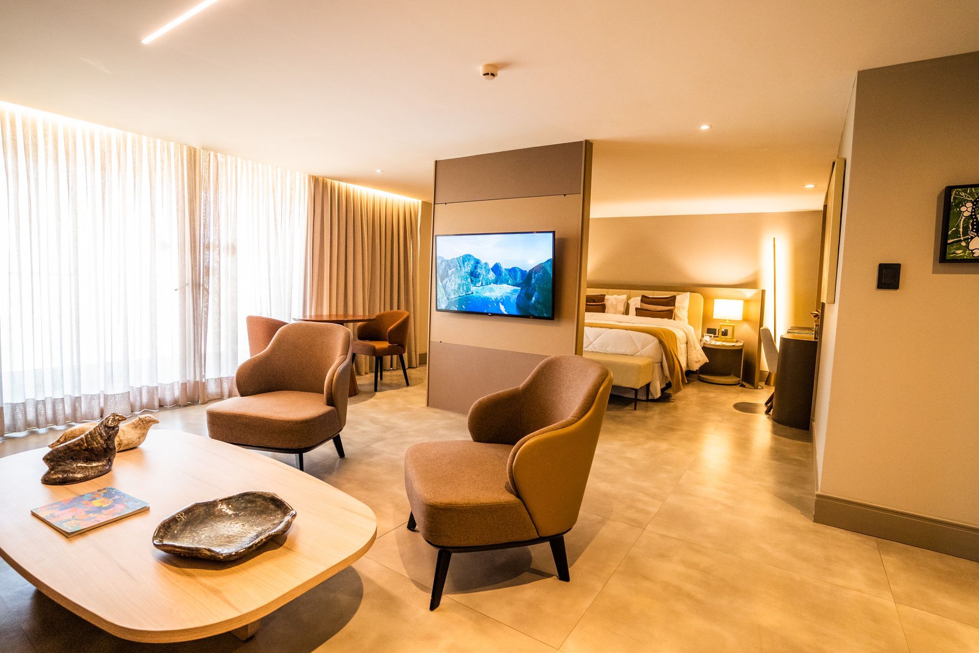 Um quarto de hotel com uma cama, cadeiras, uma mesa e uma televisão.