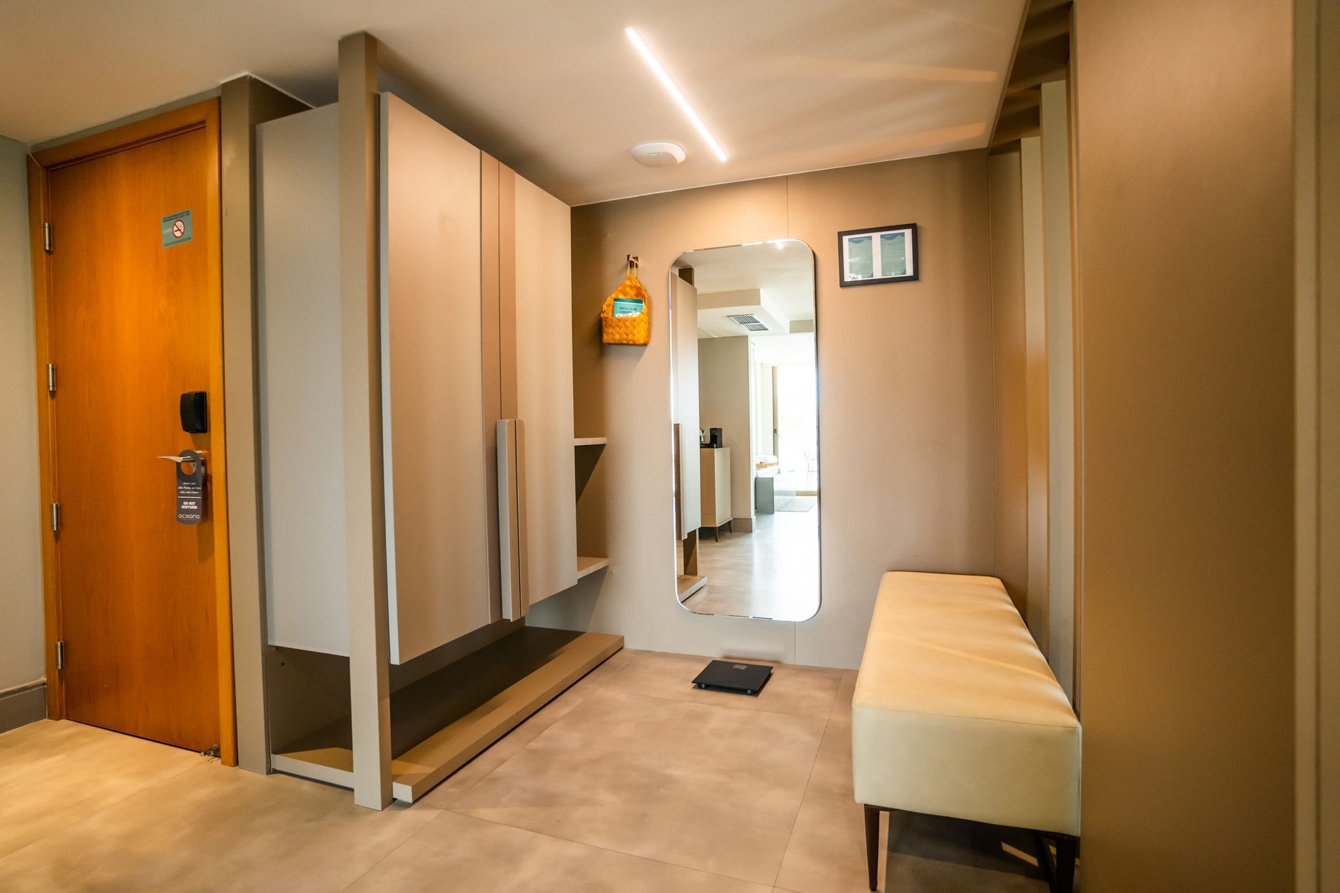 Um quarto de hotel com um banco e um espelho.