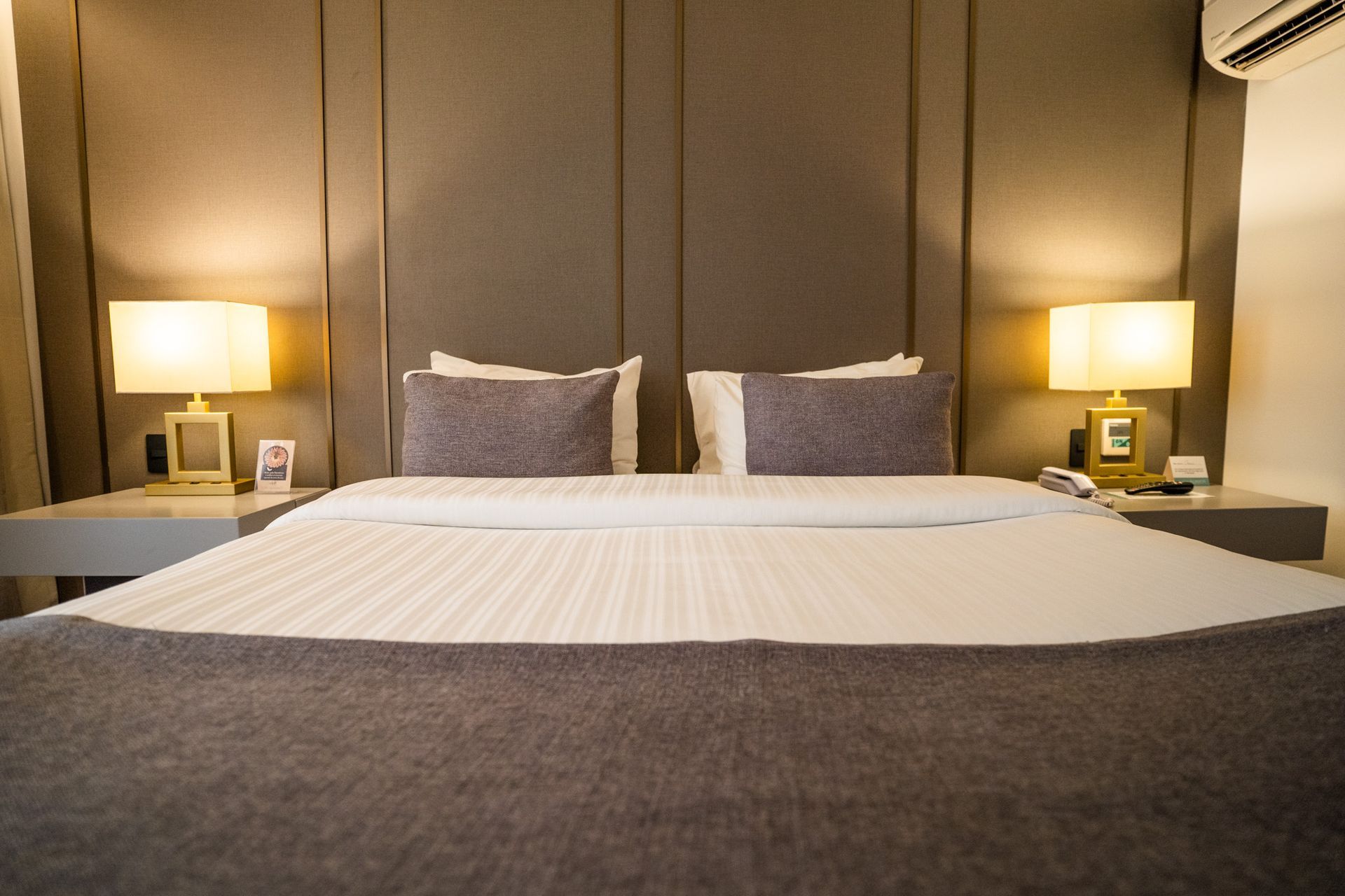 Um quarto com uma cama, dois abajures e uma cabeceira.