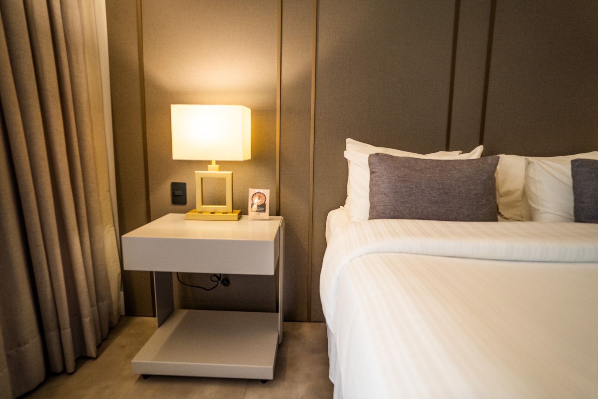 Um quarto com uma cama, mesa de cabeceira e abajur.