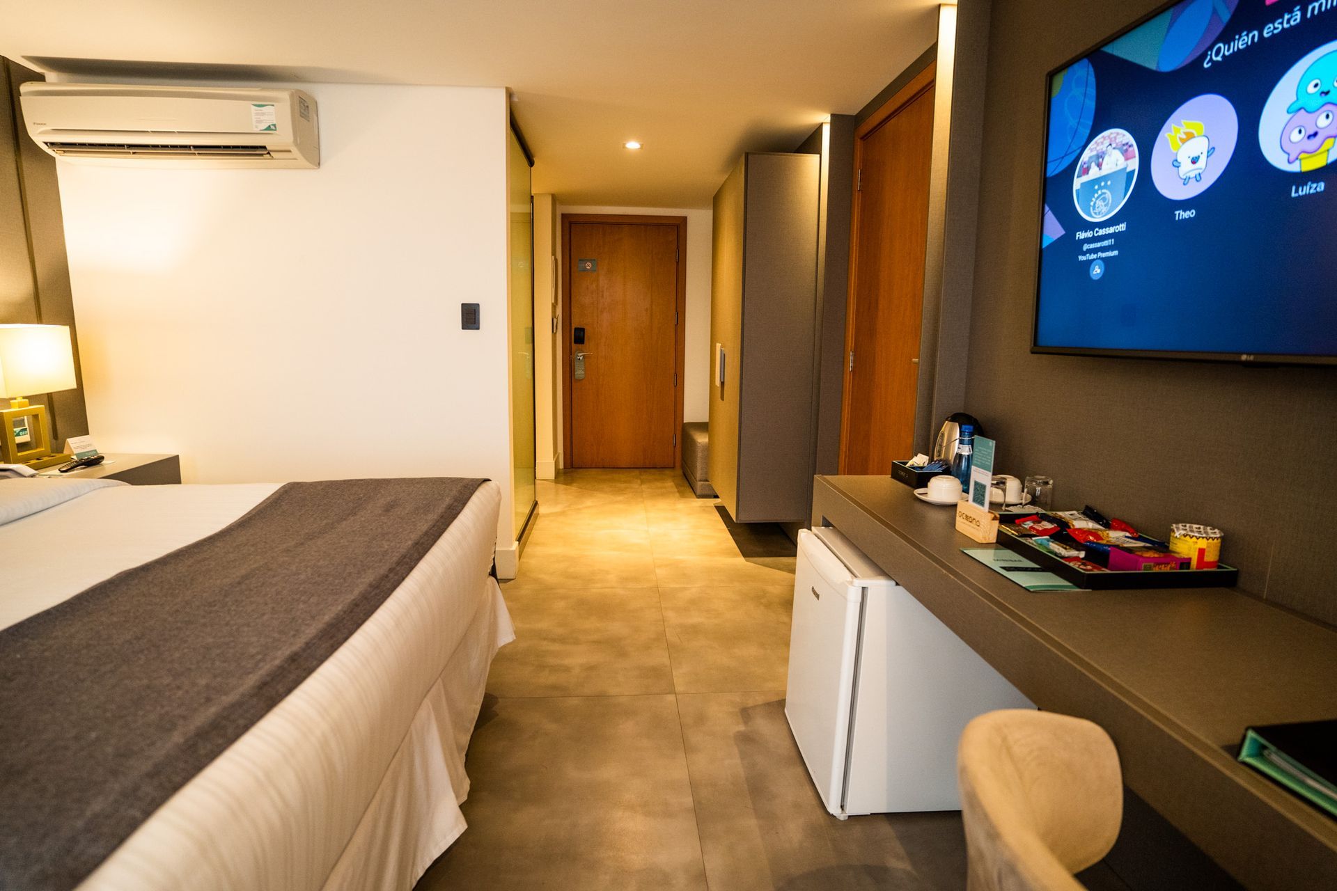 Um quarto de hotel com uma cama, escrivaninha e televisão.