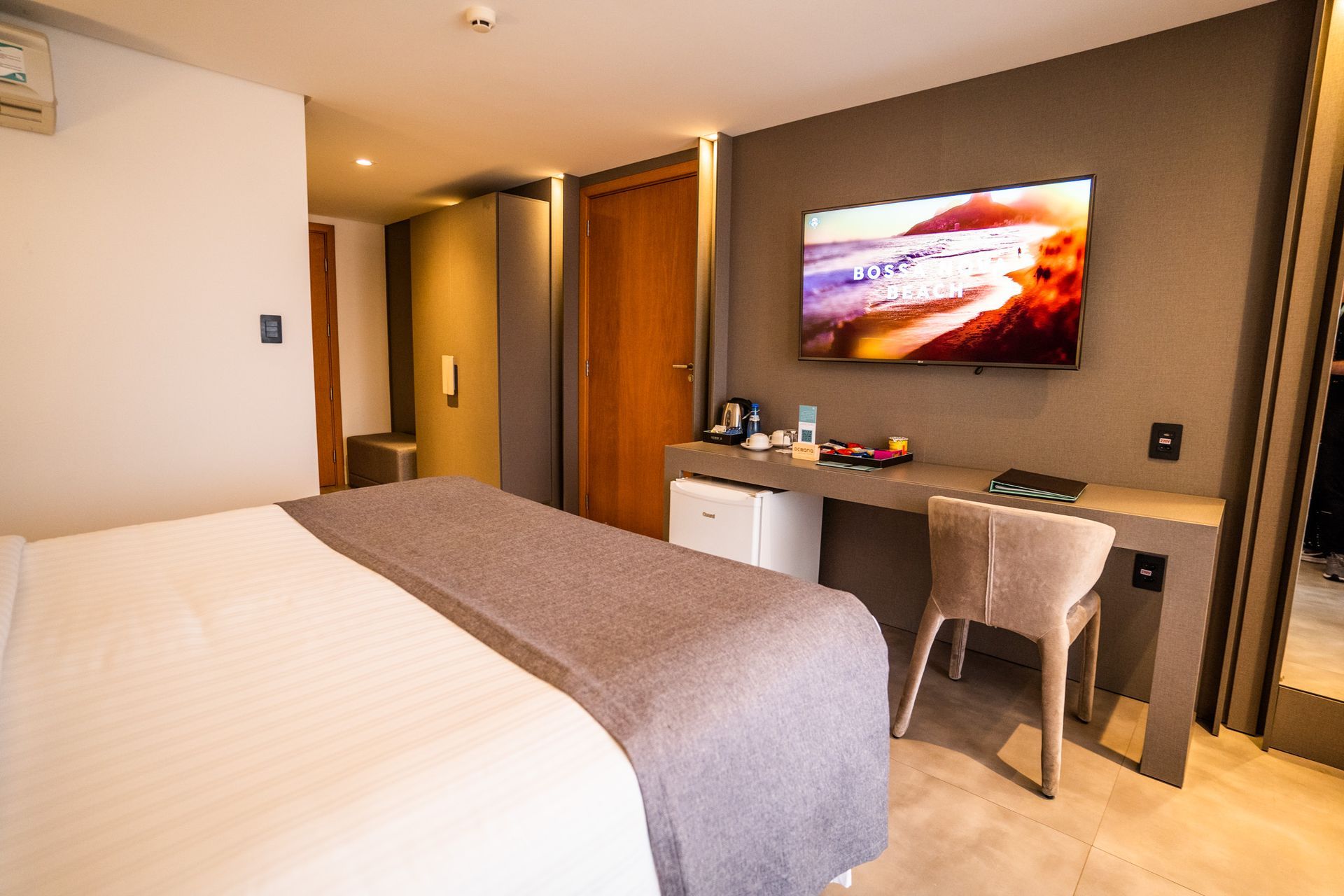 Um quarto de hotel com uma cama, escrivaninha, cadeira e televisão.