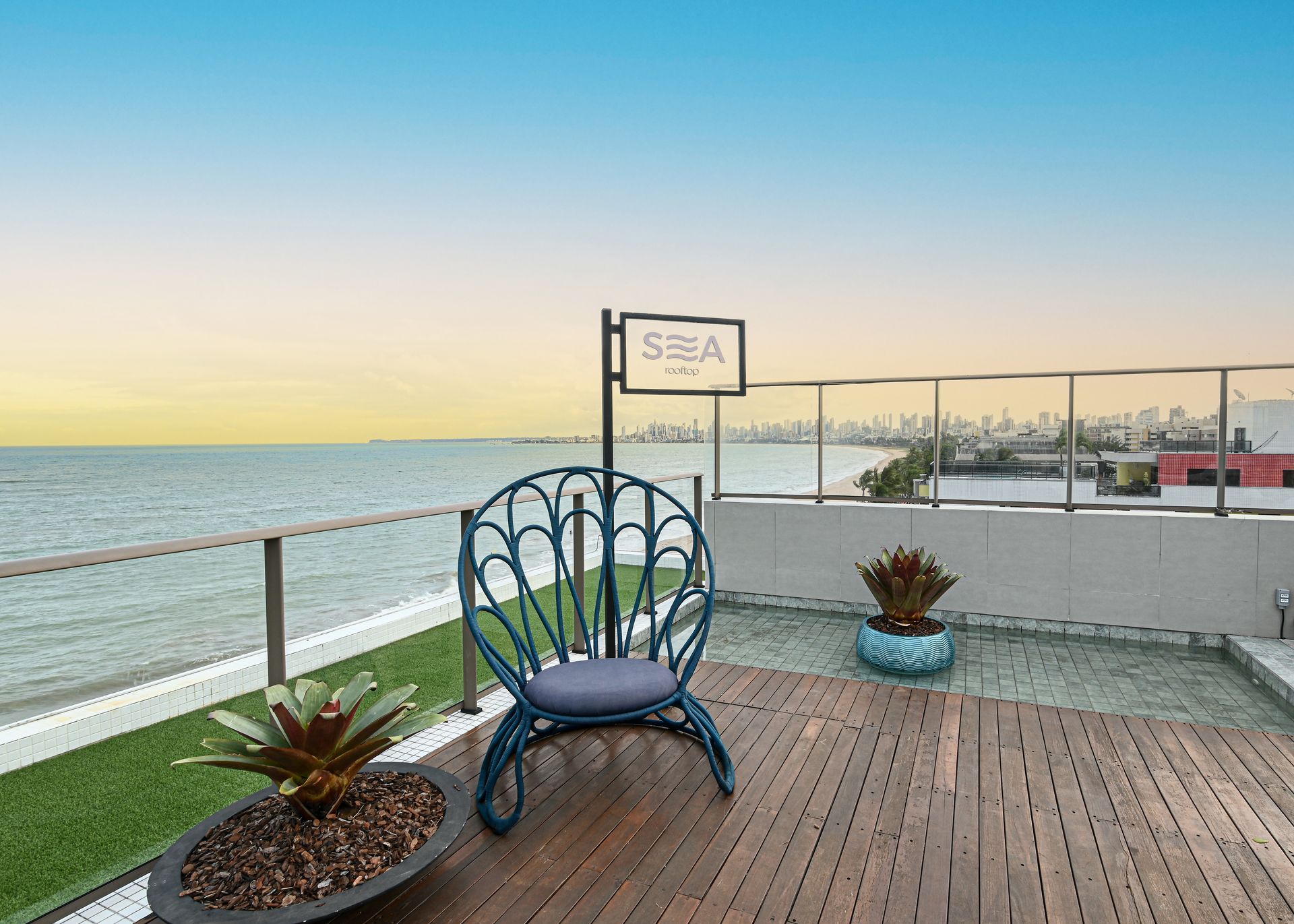 Uma cadeira está sobre um deck de madeira com vista para o oceano.