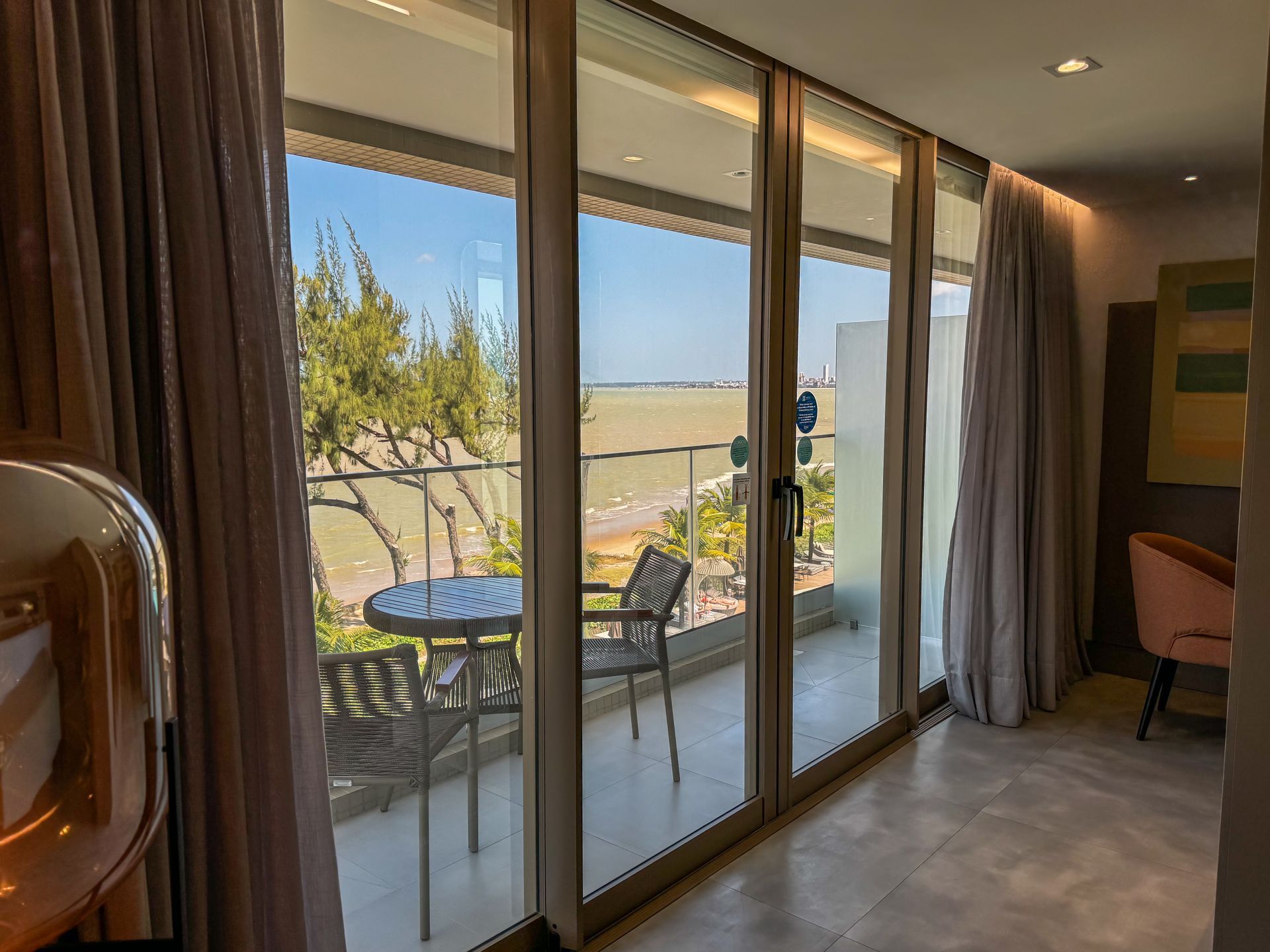 Um quarto de hotel com varanda, mesa e cadeiras.