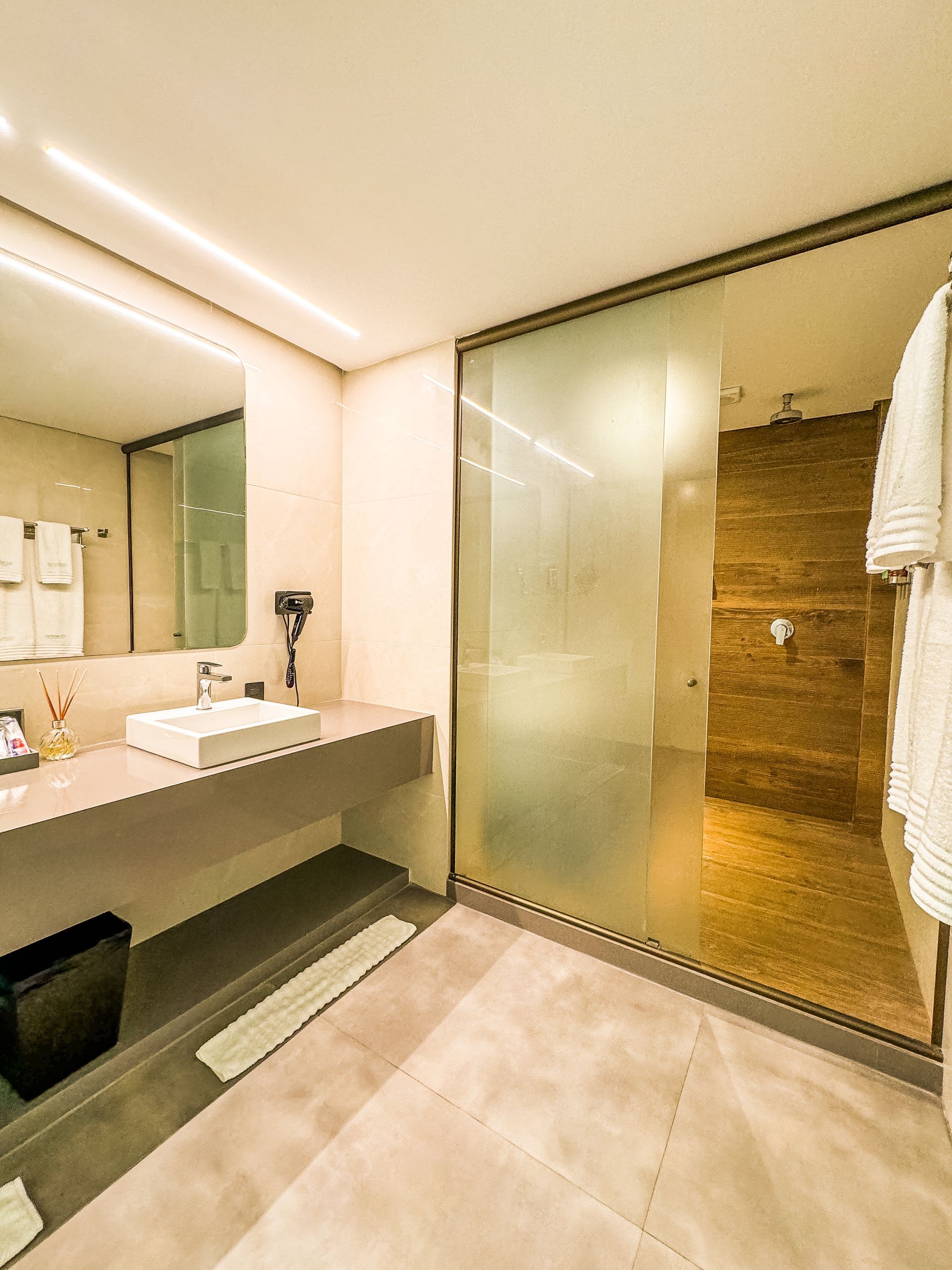 Um banheiro com pia, espelho e chuveiro.