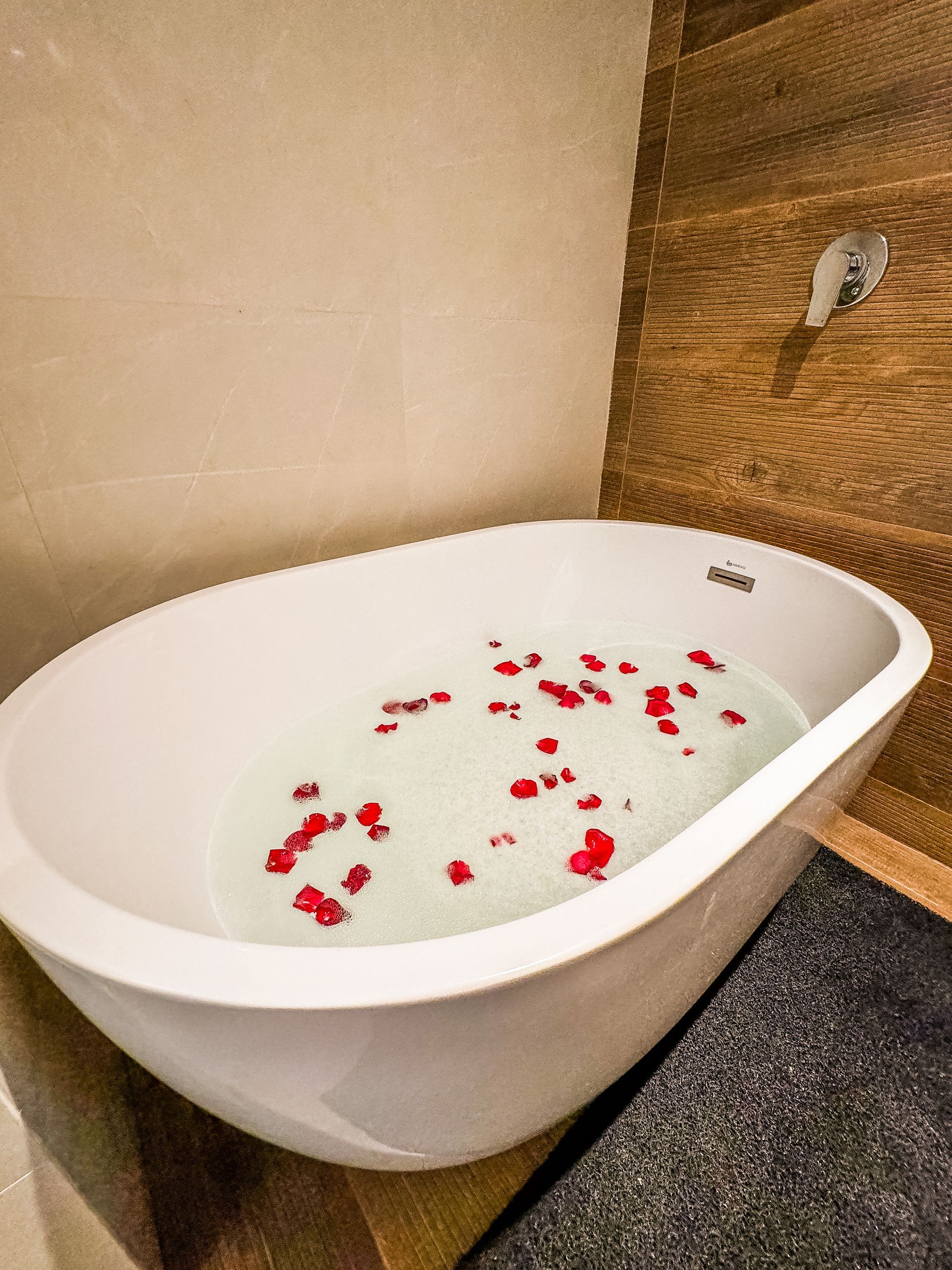 Uma banheira cheia de água e pétalas de rosa em um banheiro.