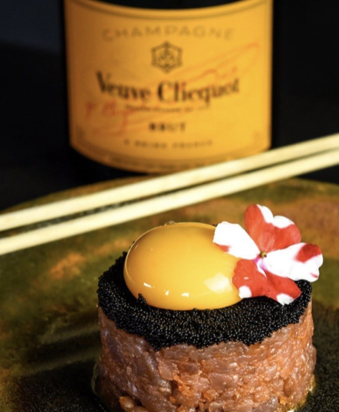 Uma garrafa de veuve clicquot fica atrás de um prato de comida
