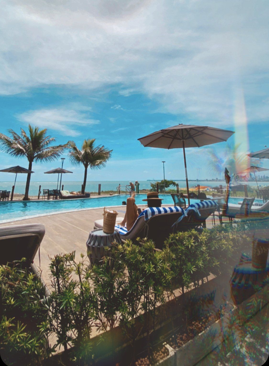 Uma piscina cercada por cadeiras e guarda-sóis em um dia ensolarado