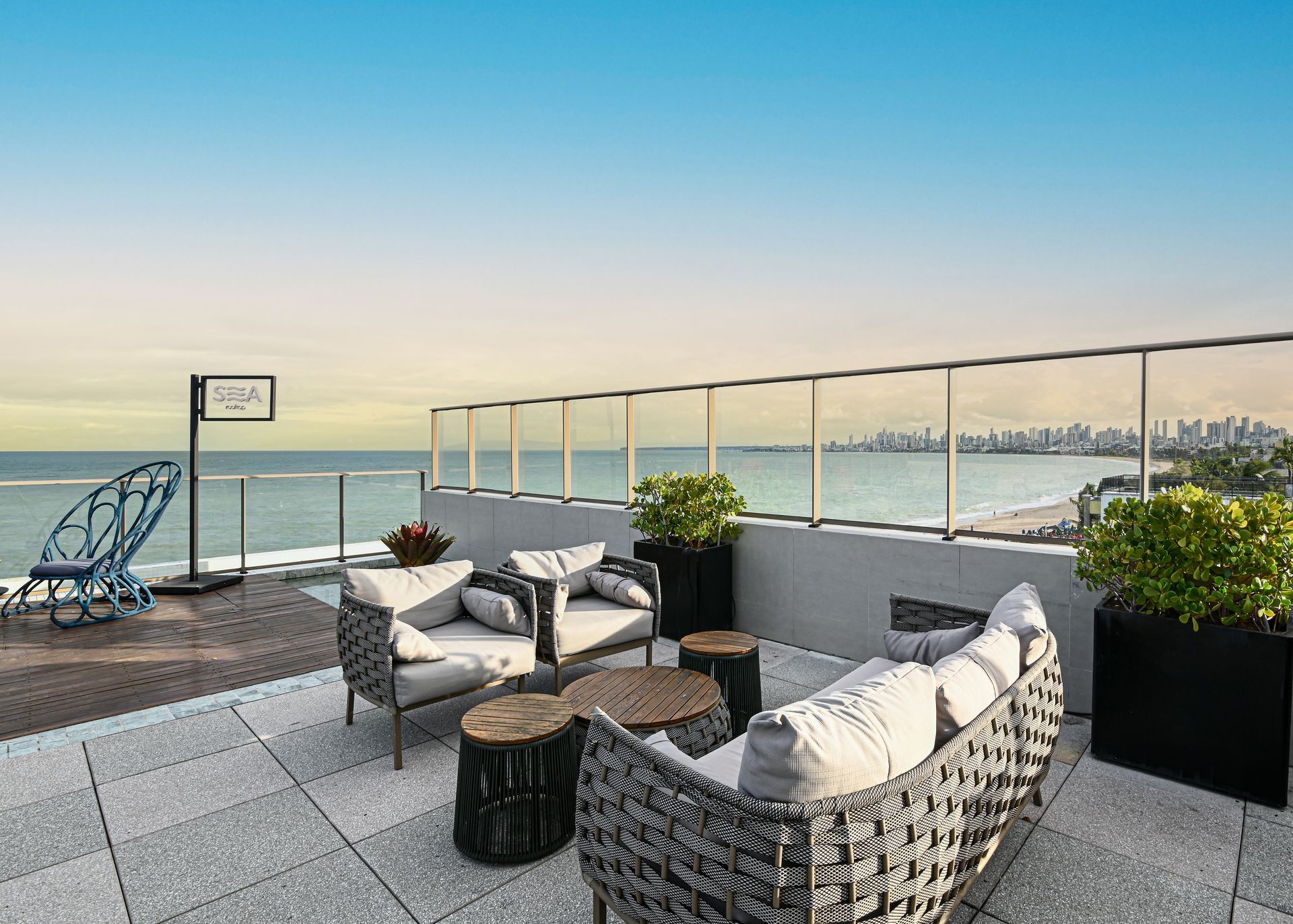 Um pátio com cadeiras e mesas com vista para o oceano.
