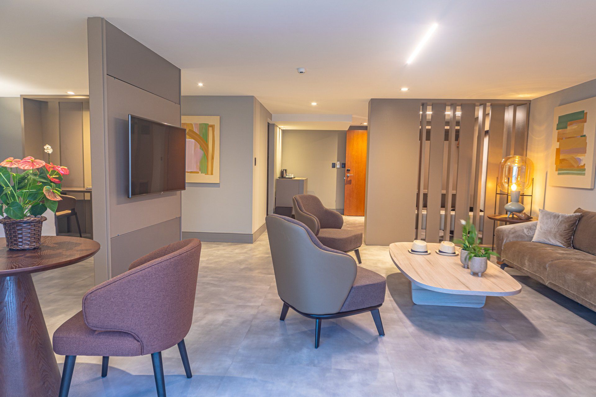 Uma sala de estar com um sofá, cadeiras, uma mesa e uma TV de tela plana.