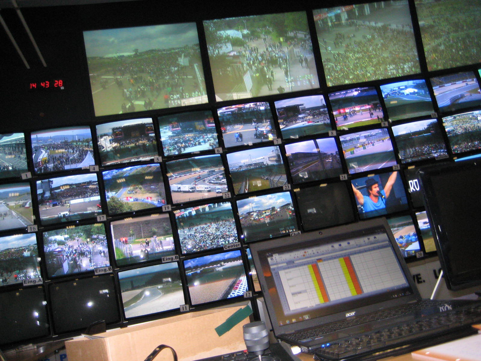 Ein Laptop steht auf einem Schreibtisch vor einer Wand aus Monitoren