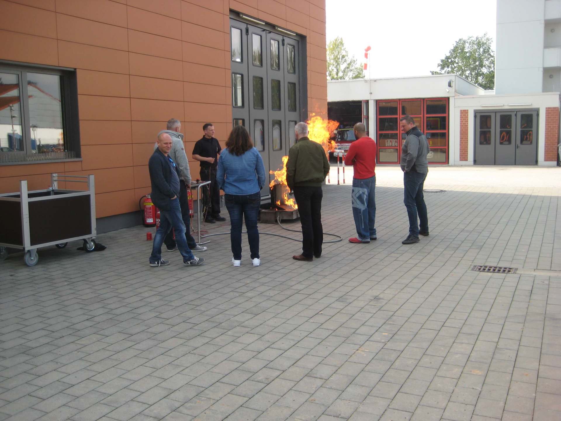 Eine Gruppe von Menschen steht um ein Feuer vor einem Gebäude