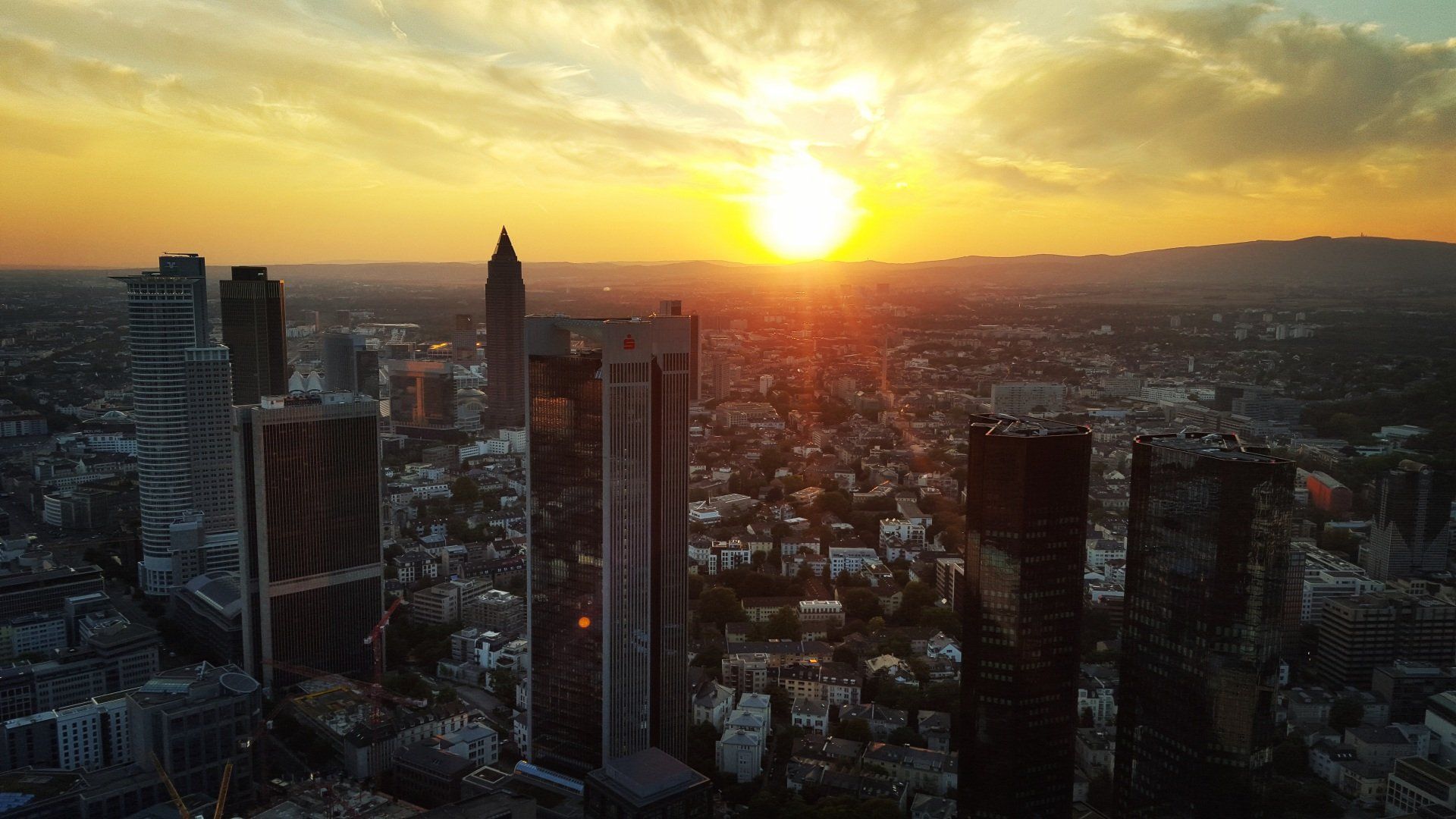 Die Sonne geht über einer Stadt mit vielen hohen Gebäuden unter