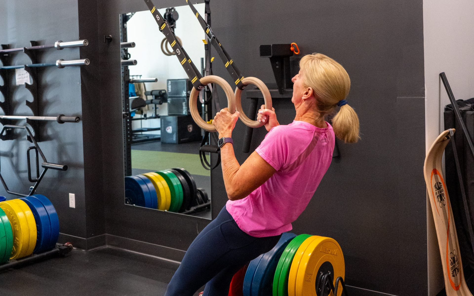 People in gym doing ab exercises, some with weights. Green turf, black equipment.