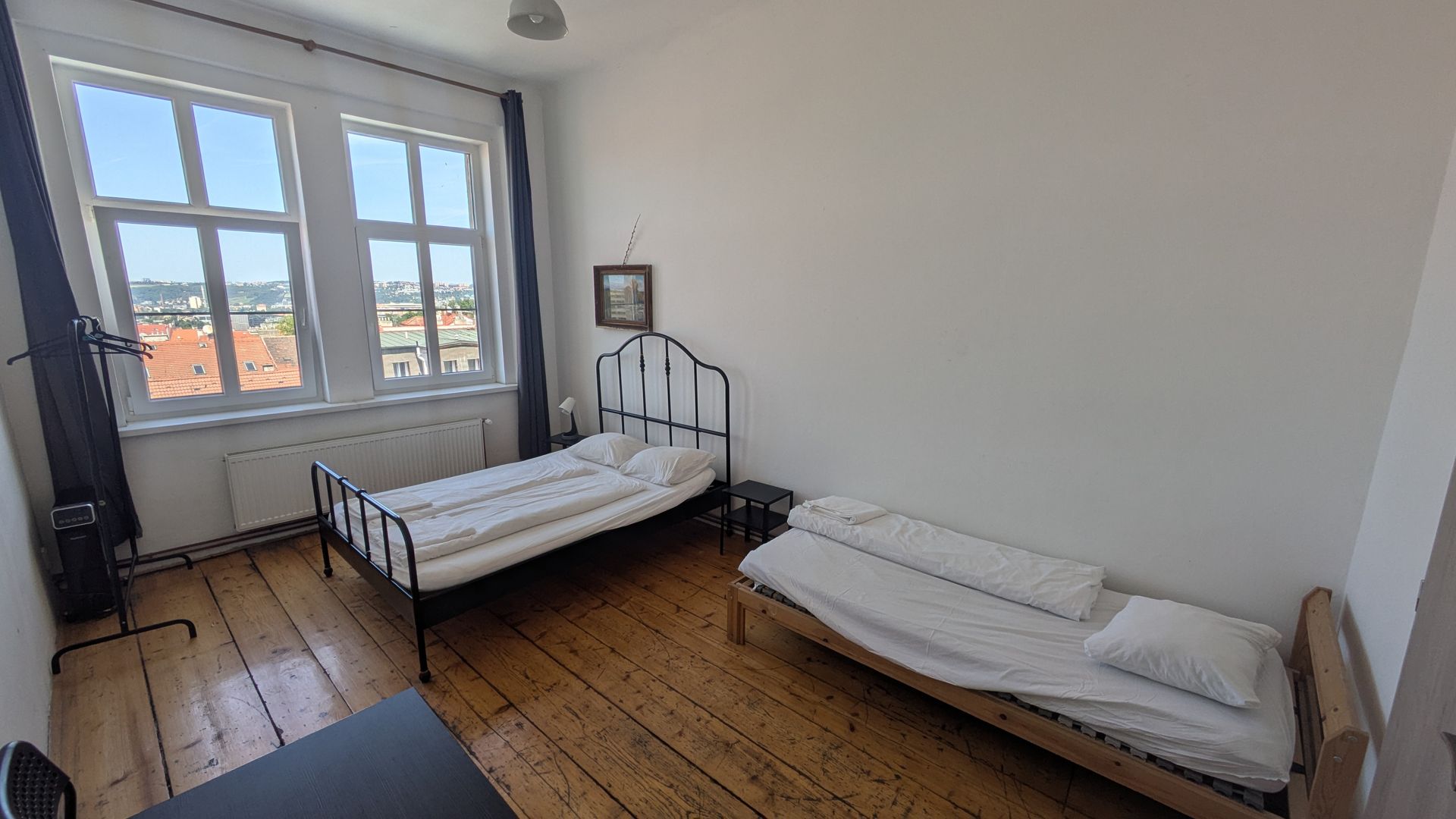 Two beds in a room with a large window. Wooden floor and white walls.