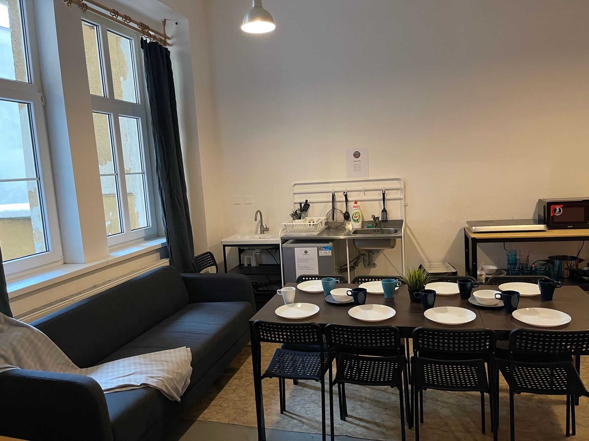 Dining room with a table set for a meal, a sofa, and a kitchenette.