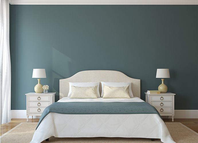 Bedroom with a teal accent wall, white bed, and matching nightstands with lamps.