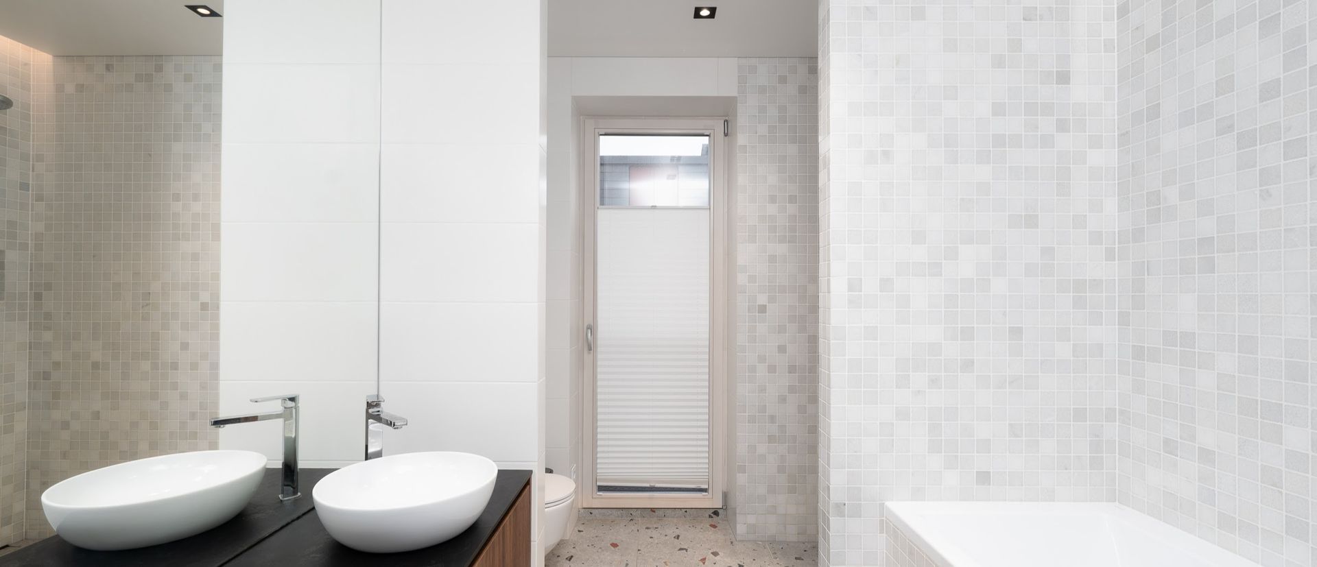 Vonios kambarys su dviem kriauklėmis ir veidrodžiu.