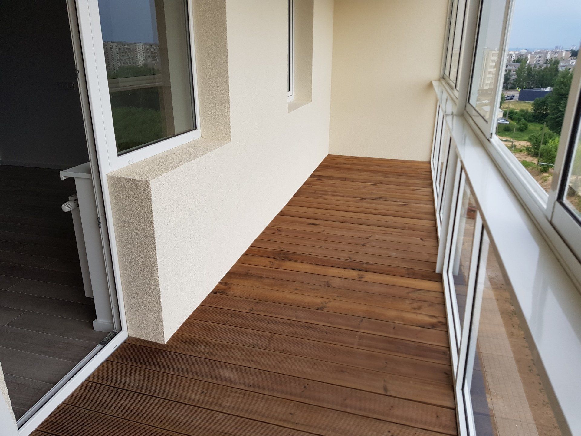 Balkonas su medinėmis grindimis ir balta siena