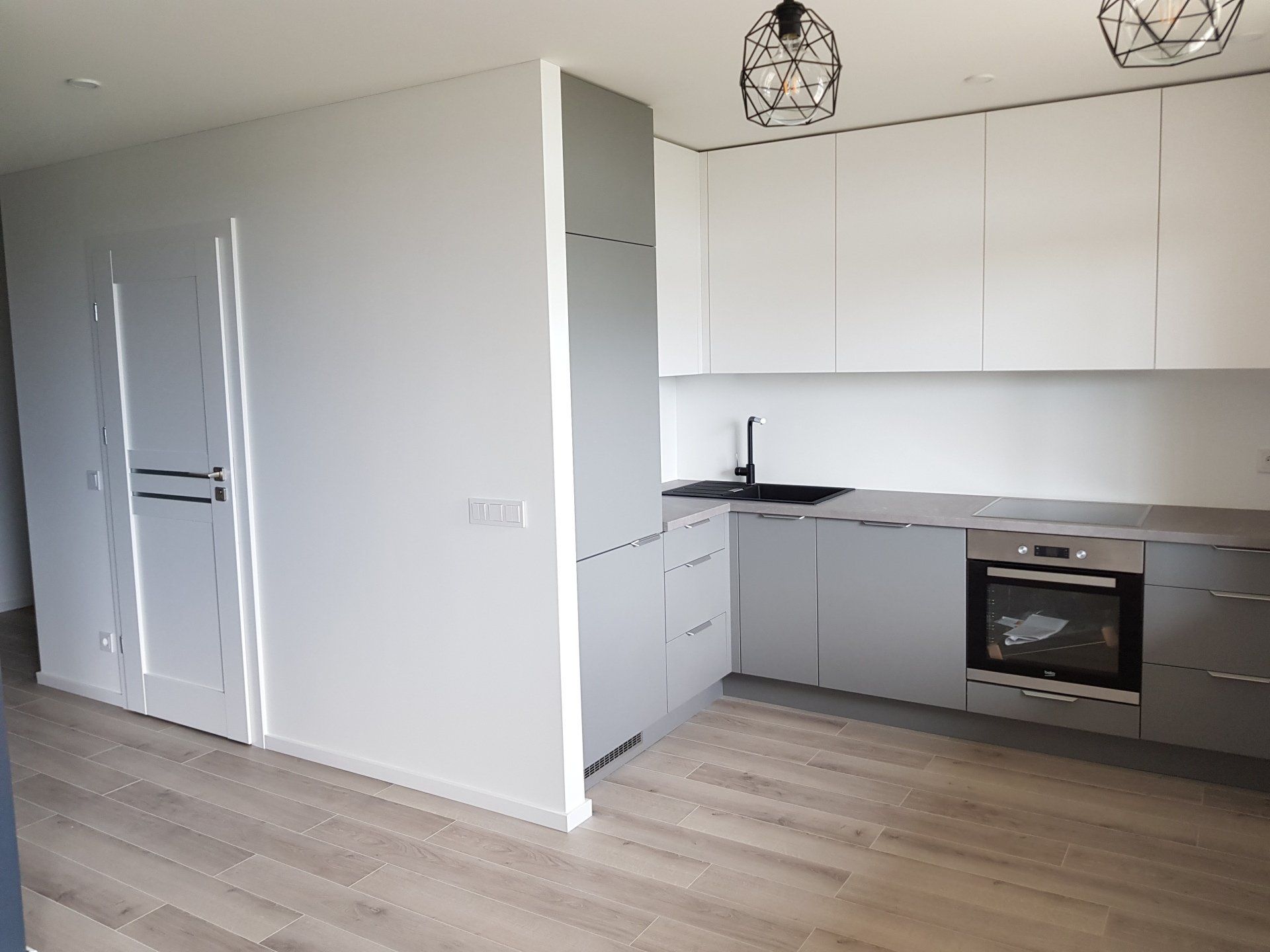 Virtuvė su nerūdijančio plieno prietaisais ir pilkomis spintelėmis