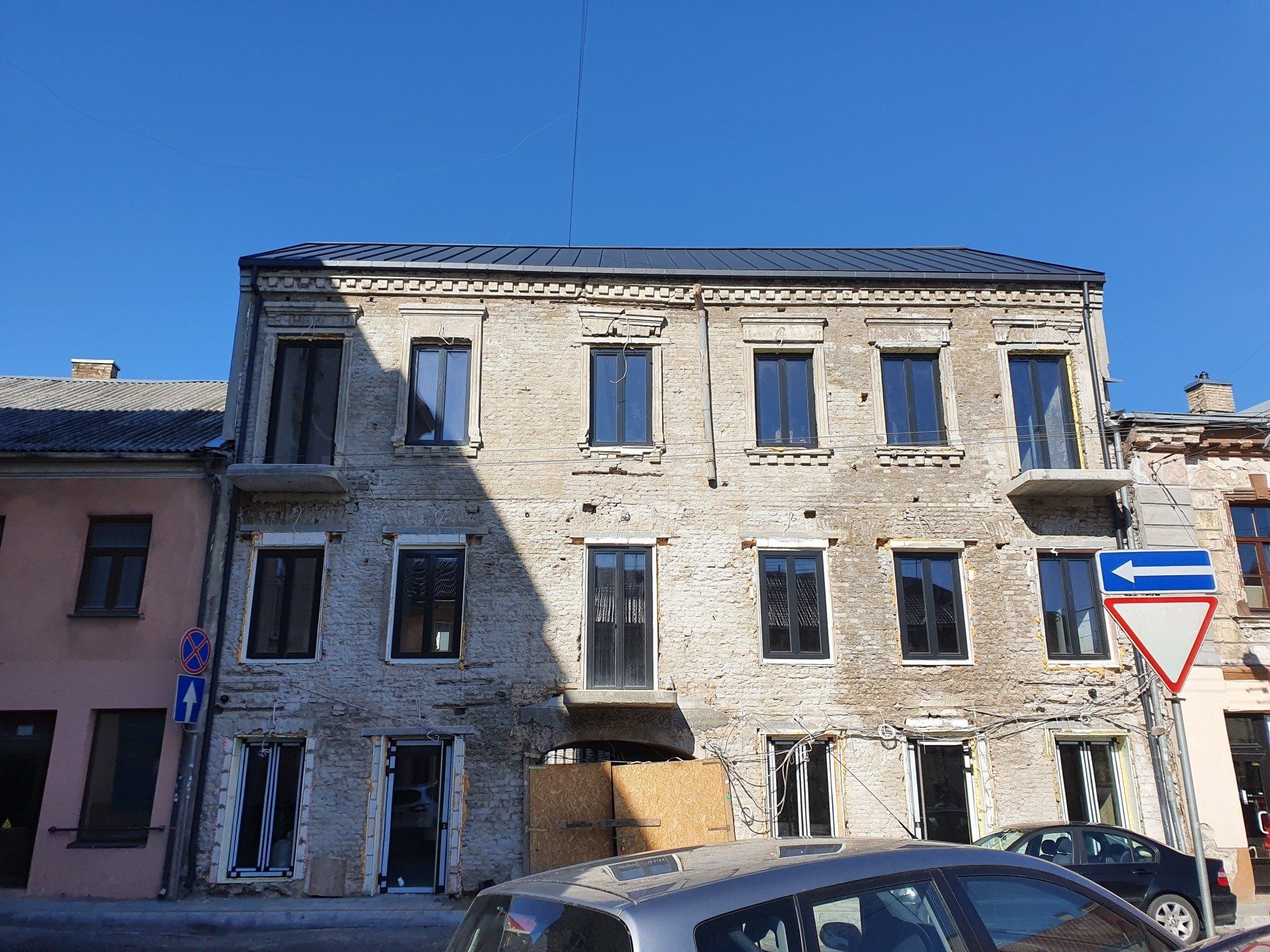 Pastatas su daugybe langų ir priešais jį pastatytu automobiliu.