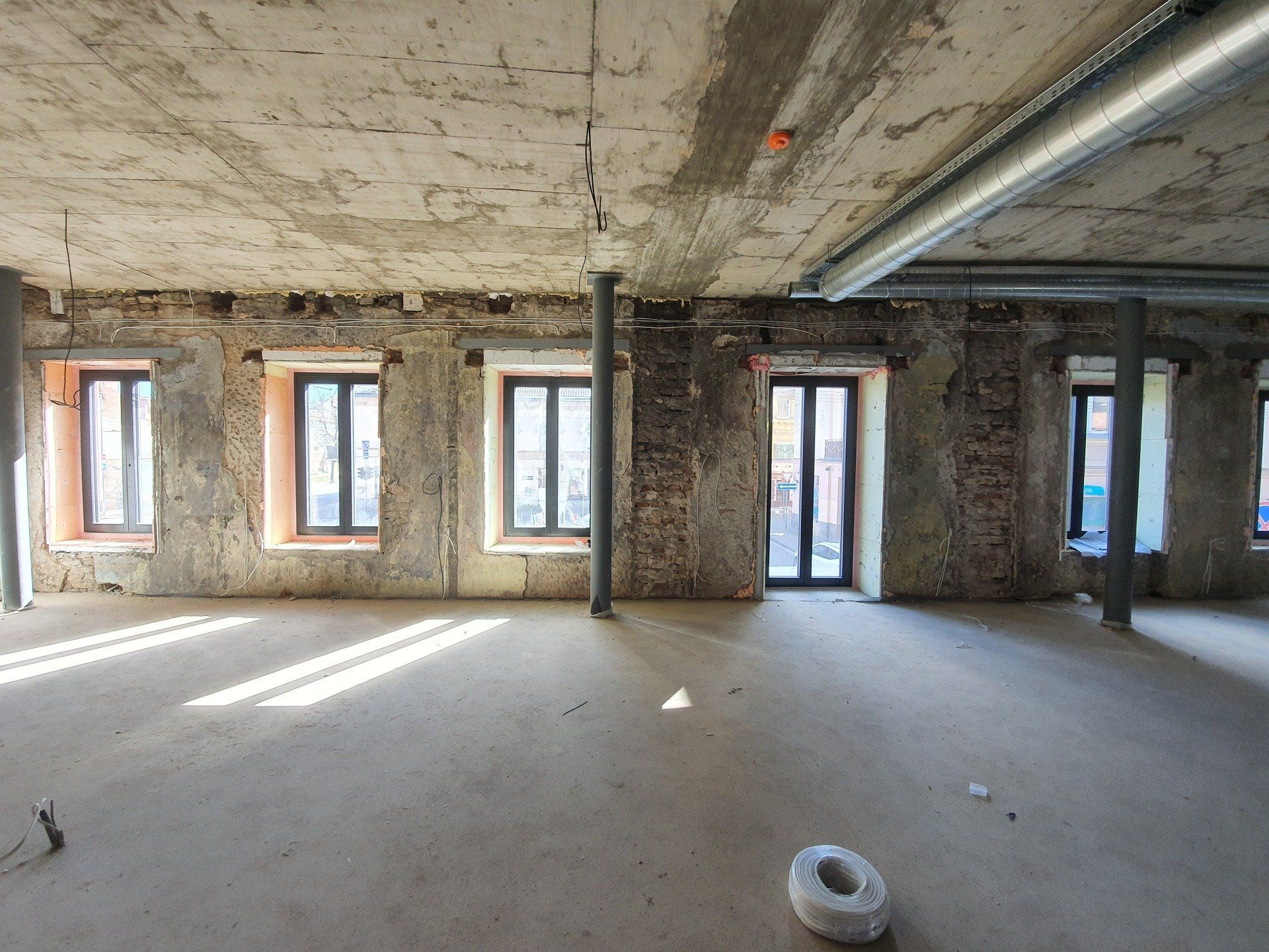 Tuščias kambarys su daugybe langų ir betoninėmis lubomis