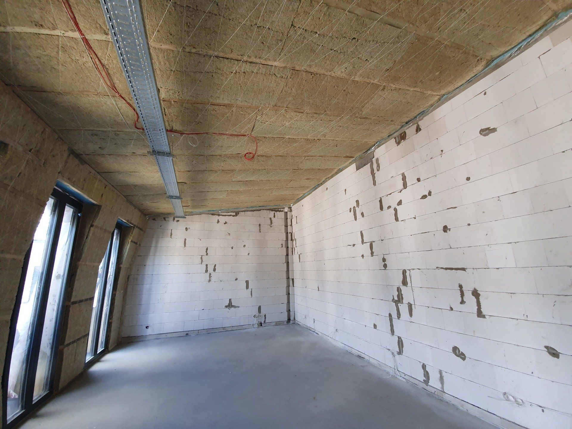 Tuščias kambarys su baltomis plytų sienomis ir juodais langais