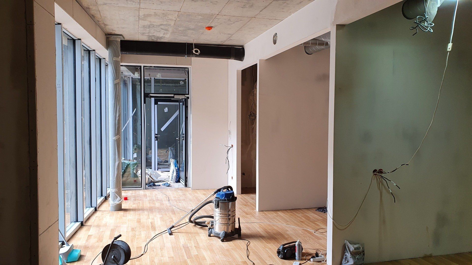 Tuščias kambarys su dulkių siurbliu viduryje.