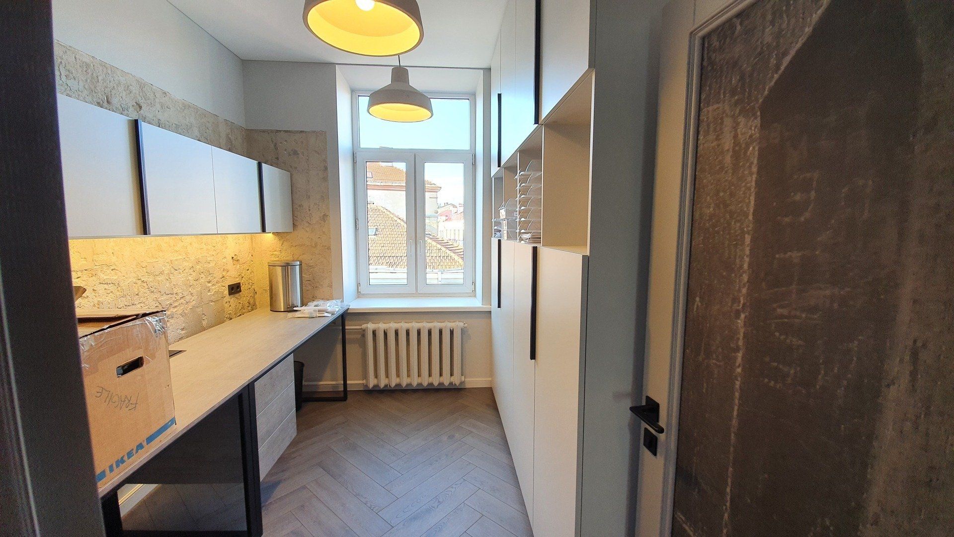 Virtuvė su ilgu stalviršiu ir langu.