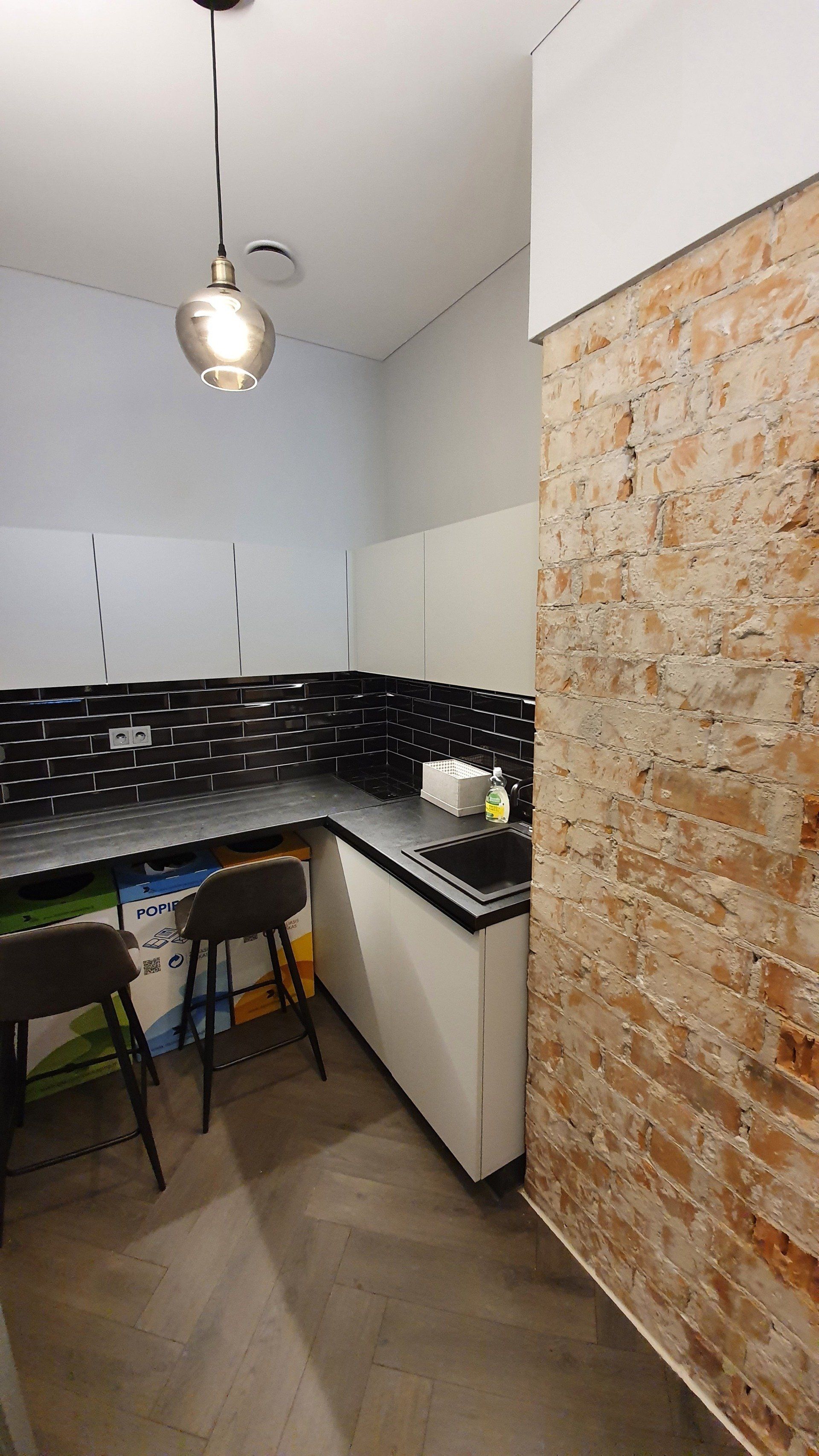 Virtuvė su plytų siena ir kriaukle.