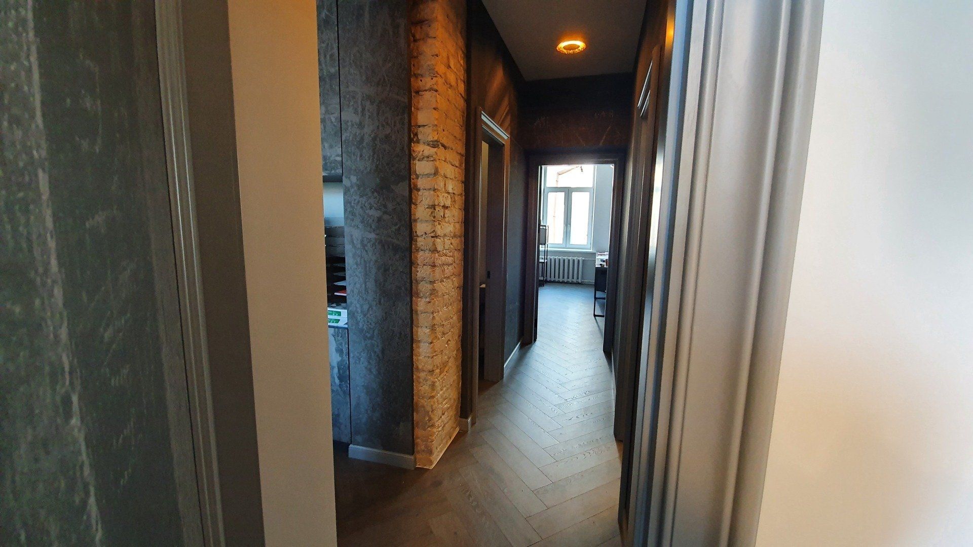 Ilgas koridorius su plytų siena ir medinėmis grindimis