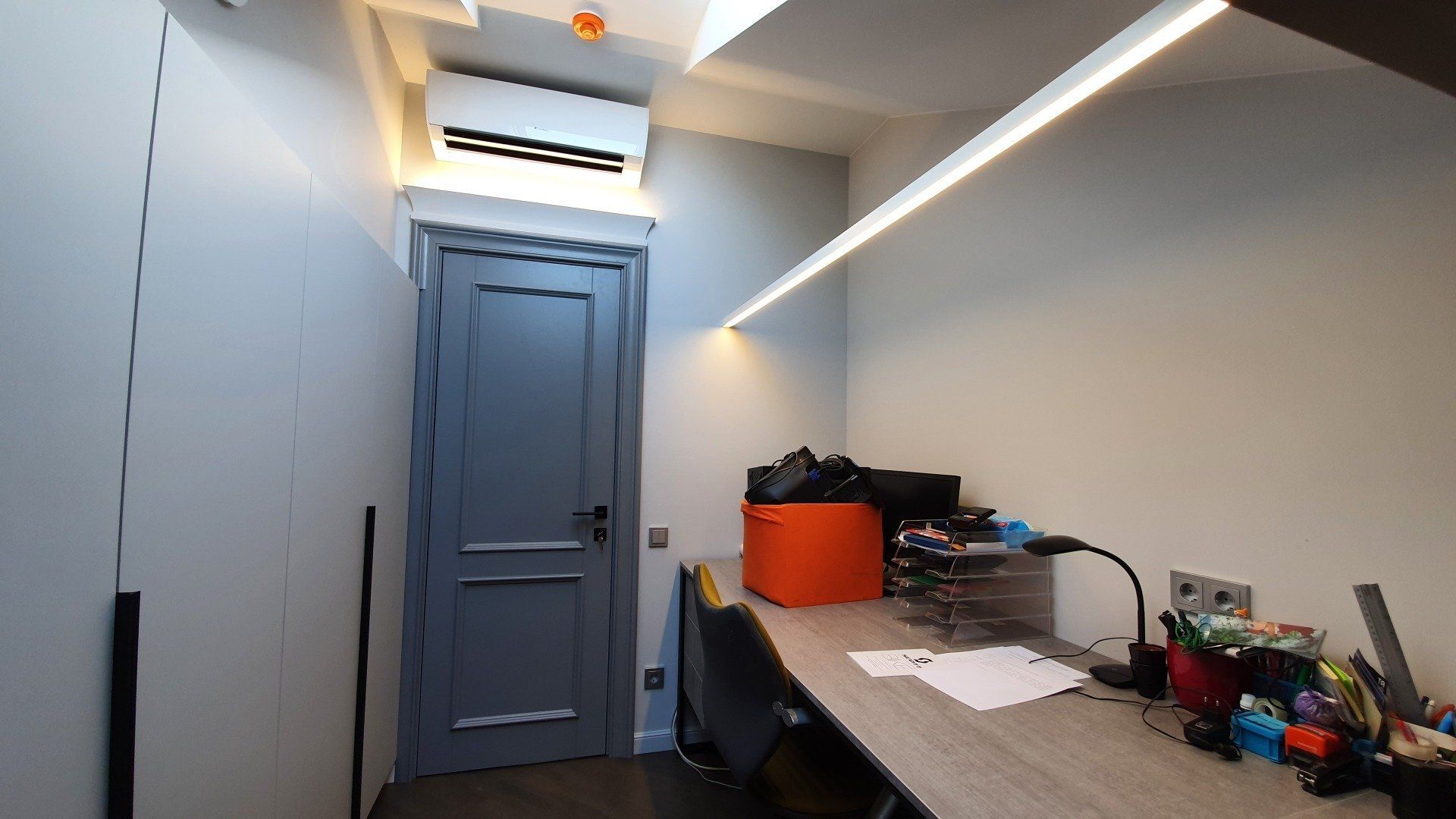 Mažas kambarys su stalu ir durimis.