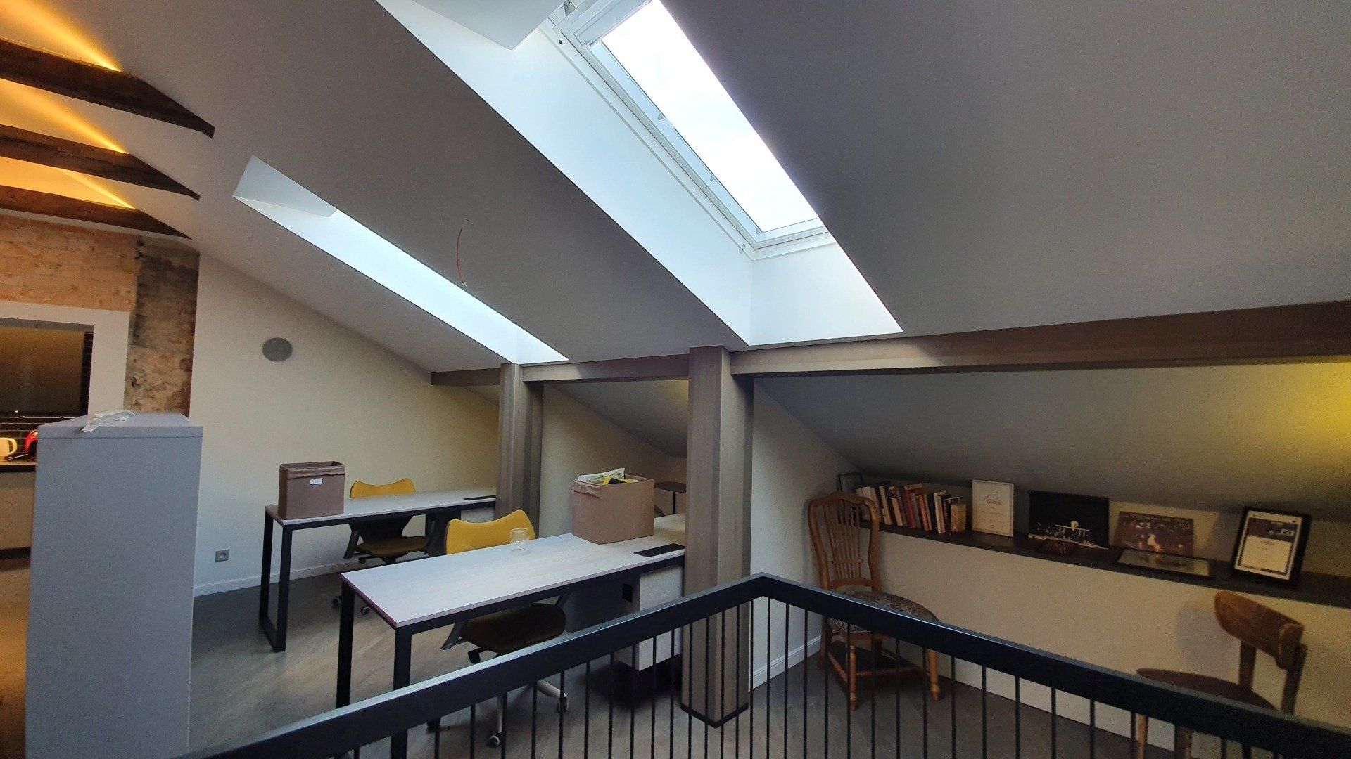 Kambarys su stoglangiu ir stalais bei kėdėmis jame