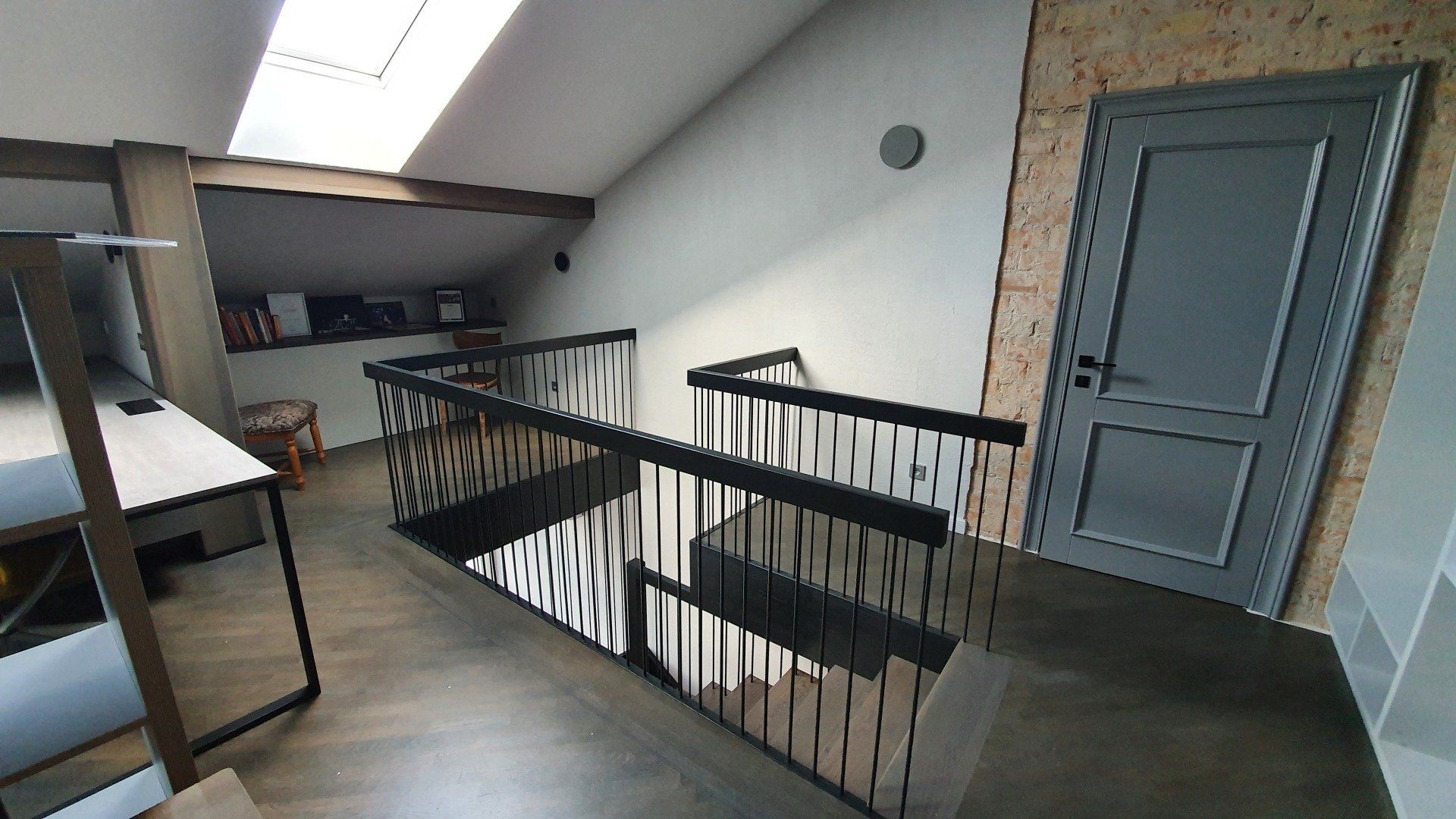 Laiptai su juodais turėklais ir pilkomis durimis