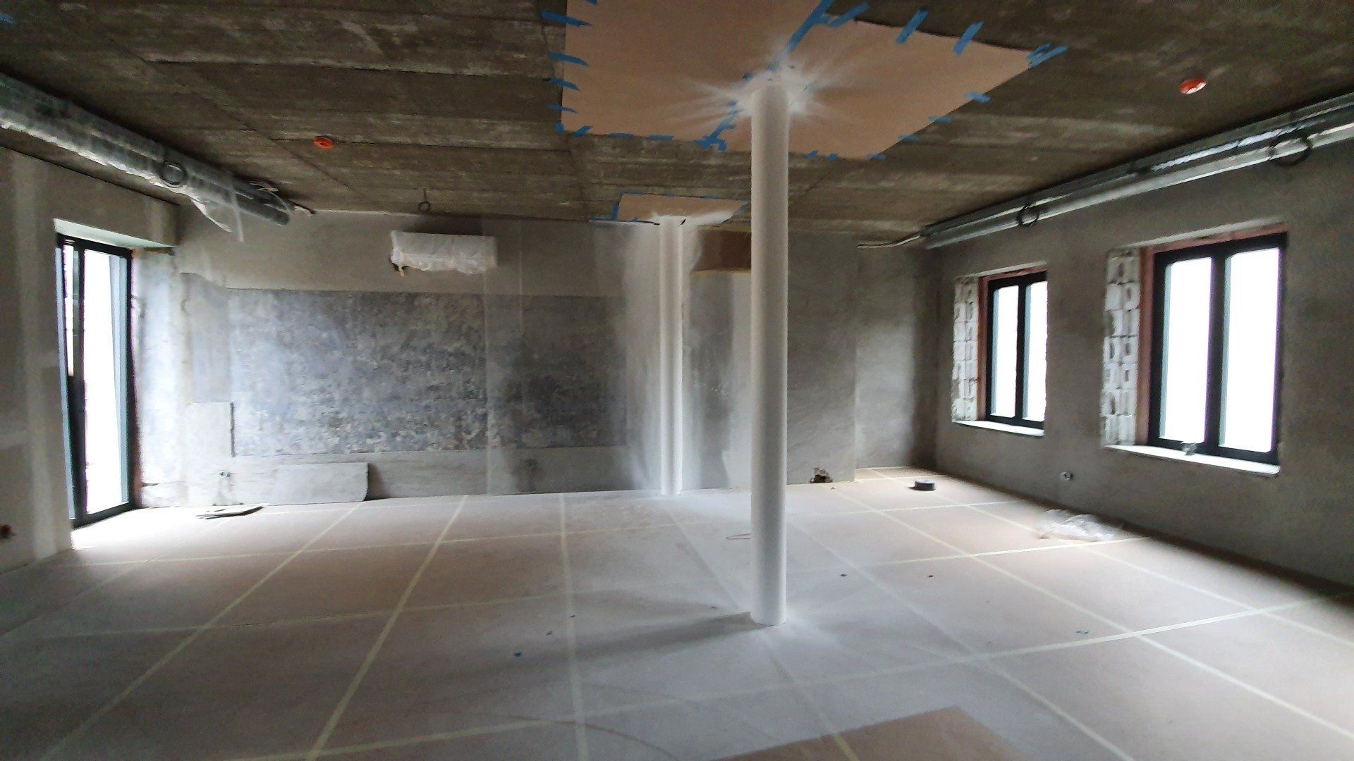 Didelis tuščias kambarys su baltu stulpu viduryje