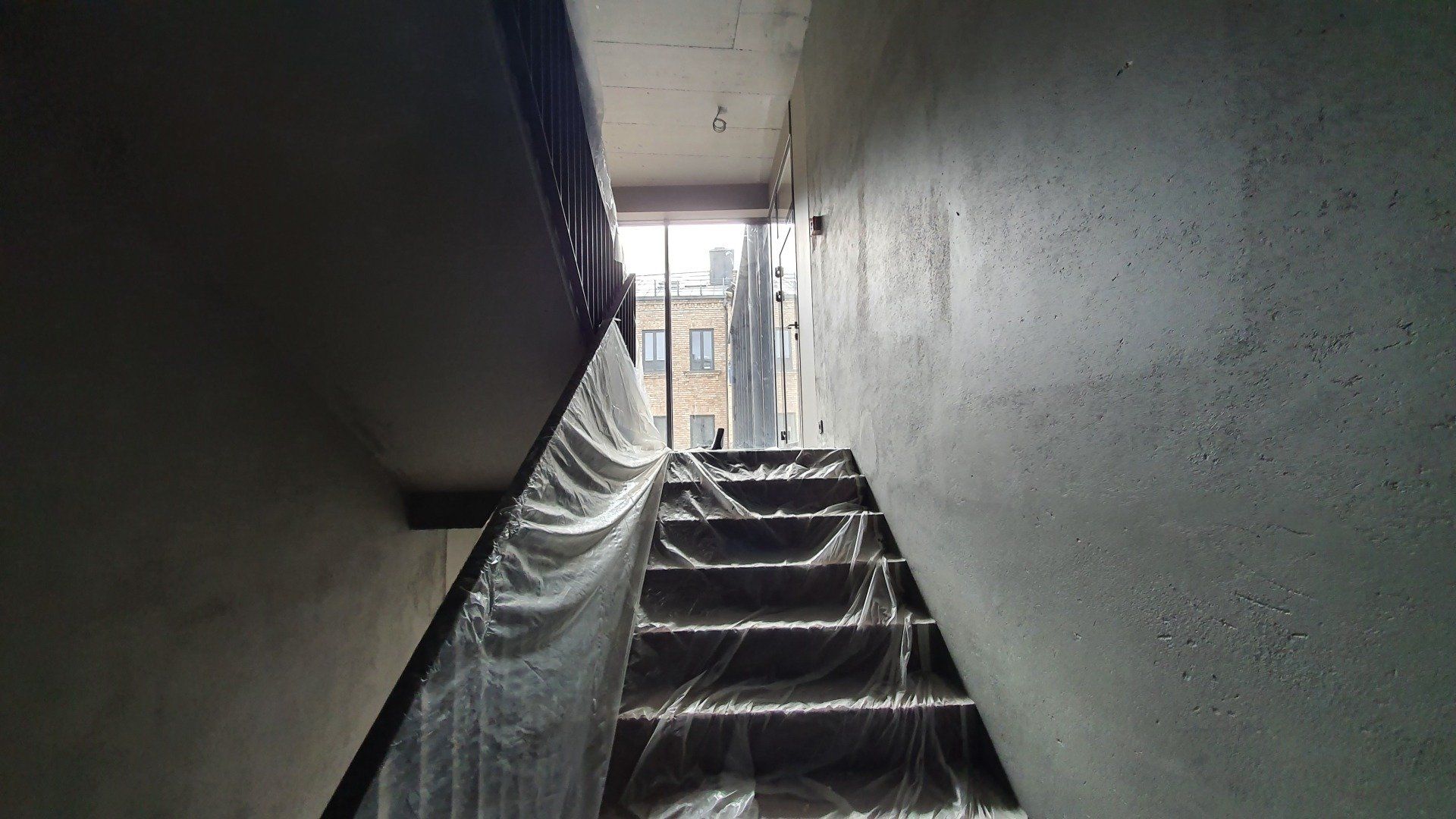 Laiptų komplektas, apdengtas plastikine plėvele statomame pastate.