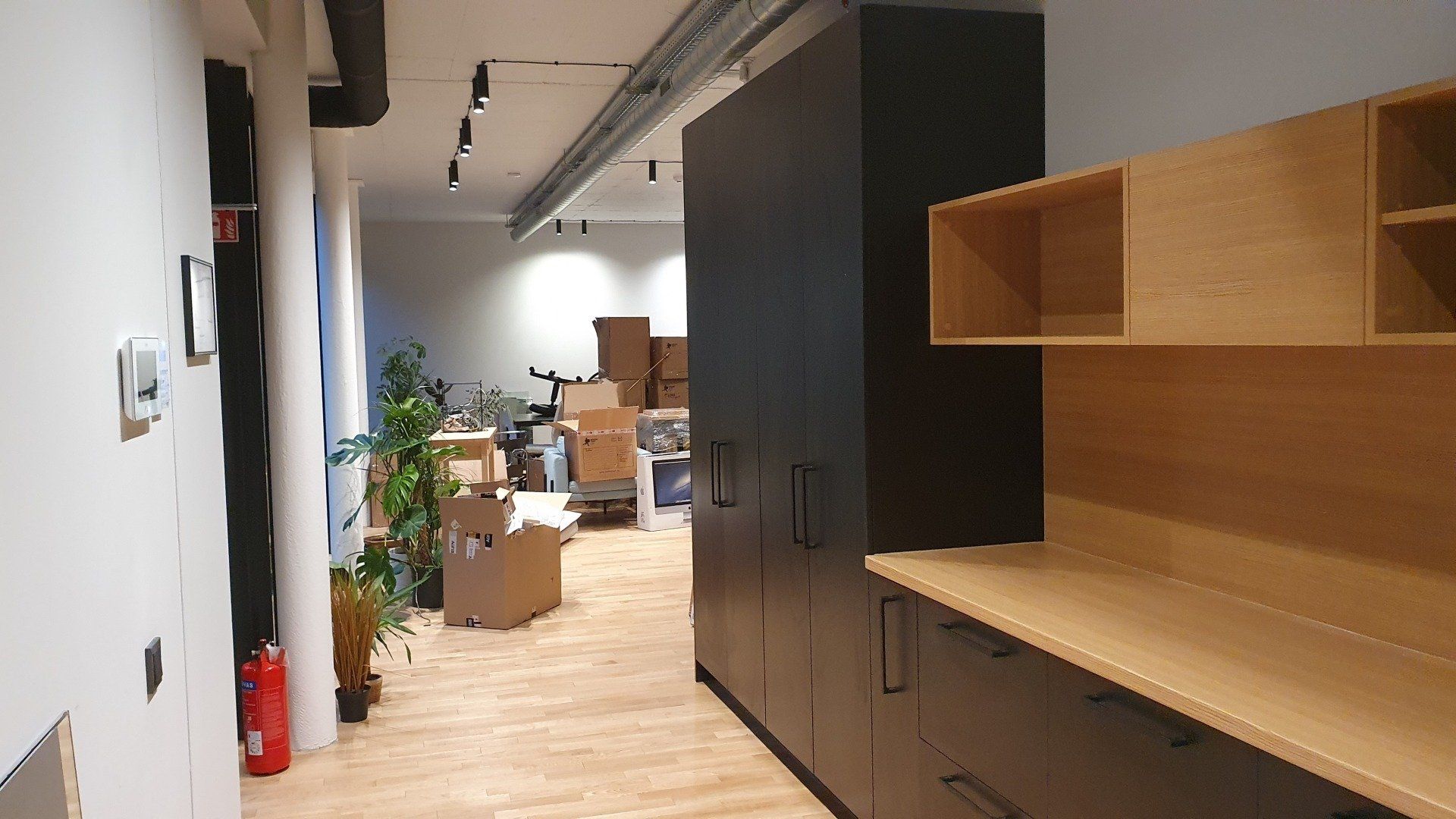 Prieškambaris su medinėmis grindimis ir juodomis spintelėmis biure