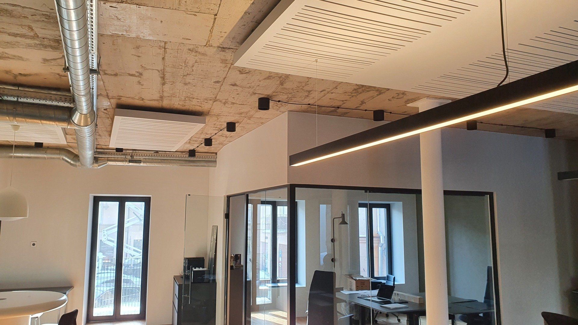 Didelis kambarys su daugybe langų ir skylėtomis lubomis.