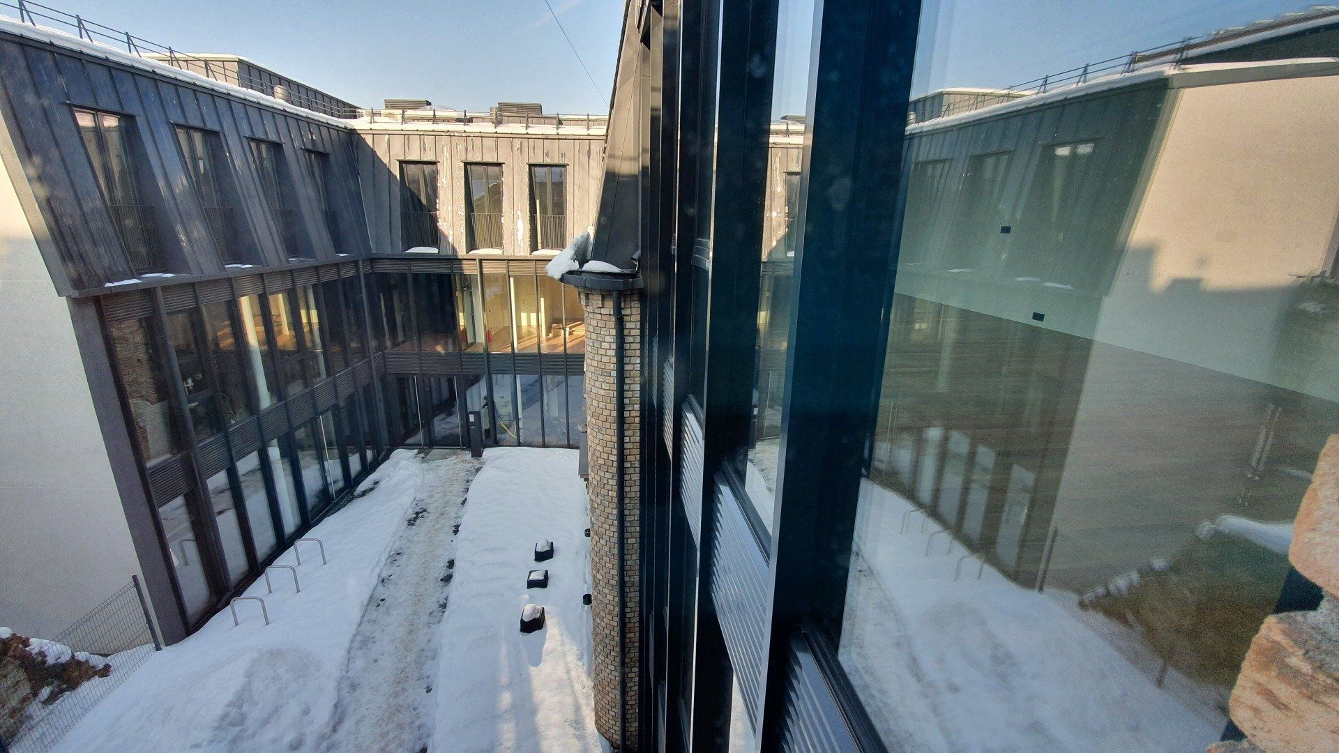 Pastato vaizdas pro langą, ant žemės – sniegas.