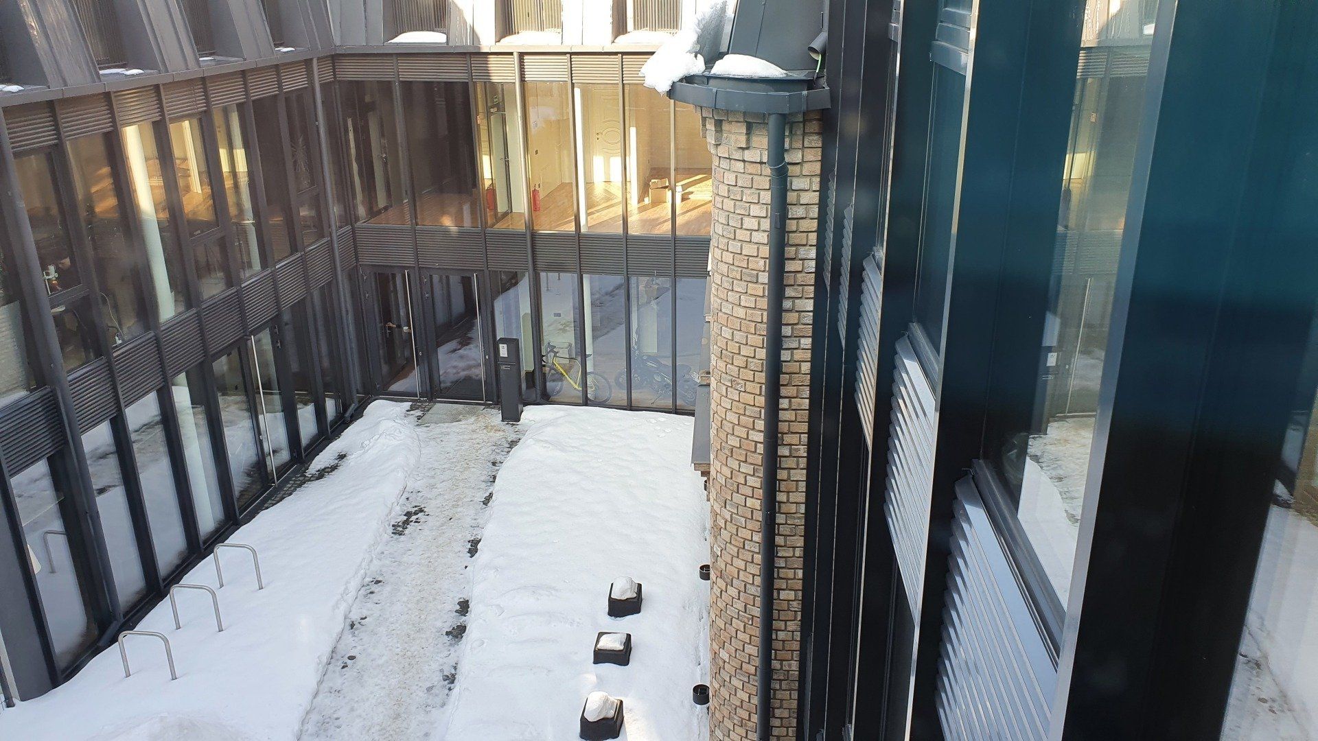 Paukščių lesyklėlė stovi sniege priešais pastatą.